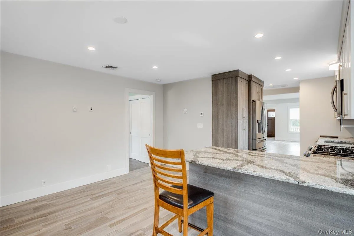 Kitchen featuring light stone counters, recessed lighting, stainless steel appliances, light wood-type flooring, and a kitchen breakfast bar Kitchen featuring light stone counters, recessed lighting, stainless steel appliances, light wood-type flooring, and a kitchen breakfast bar
