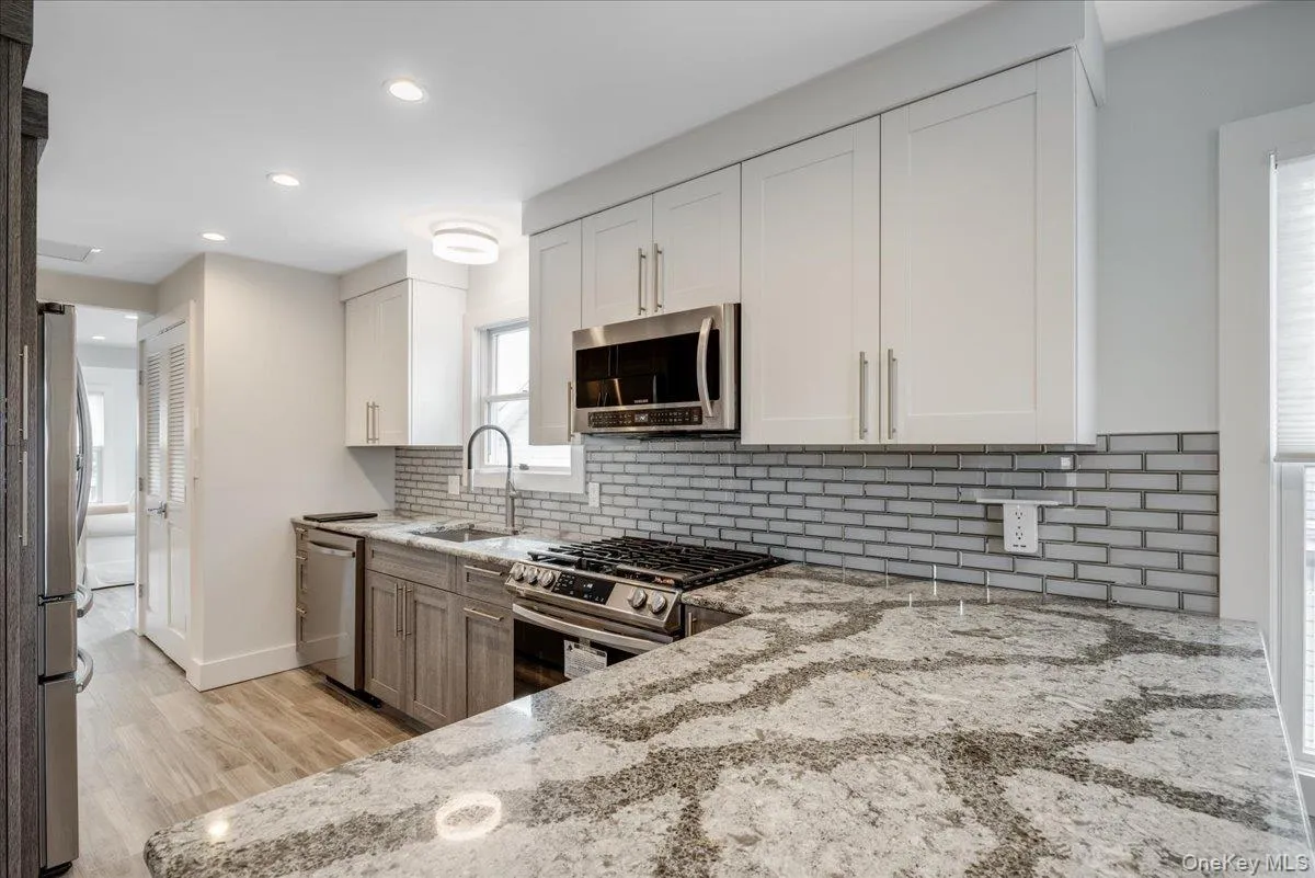 Kitchen with white cabinetry, appliances with stainless steel finishes, light stone counters, recessed lighting, and tasteful backsplash Kitchen with white cabinetry, appliances with stainless steel finishes, light stone counters, recessed lighting, and tasteful backsplash