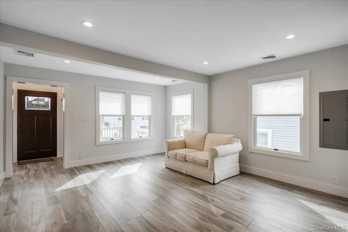 Living area with electric panel, light wood-style floors, healthy amount of natural light, and recessed lighting Living area with electric panel, light wood-style floors, healthy amount of natural light, and recessed lighting