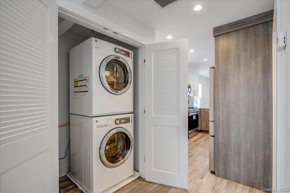 Laundry room featuring estacked washer and dryer, recessed lighting, and light wood-type flooring Laundry room featuring estacked washer and dryer, recessed lighting, and light wood-type flooring