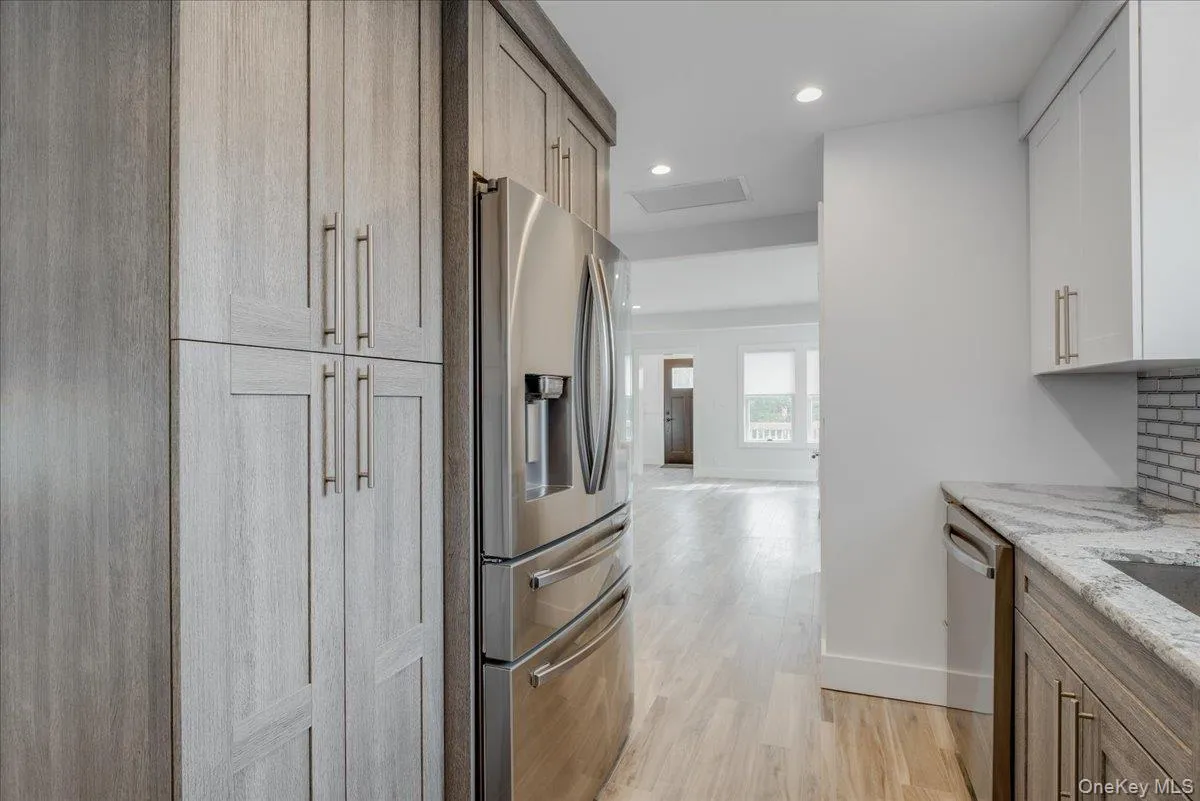 Kitchen with stainless steel appliances, light stone countertops, light wood-style floors, and recessed lighting Kitchen with stainless steel appliances, light stone countertops, light wood-style floors, and recessed lighting