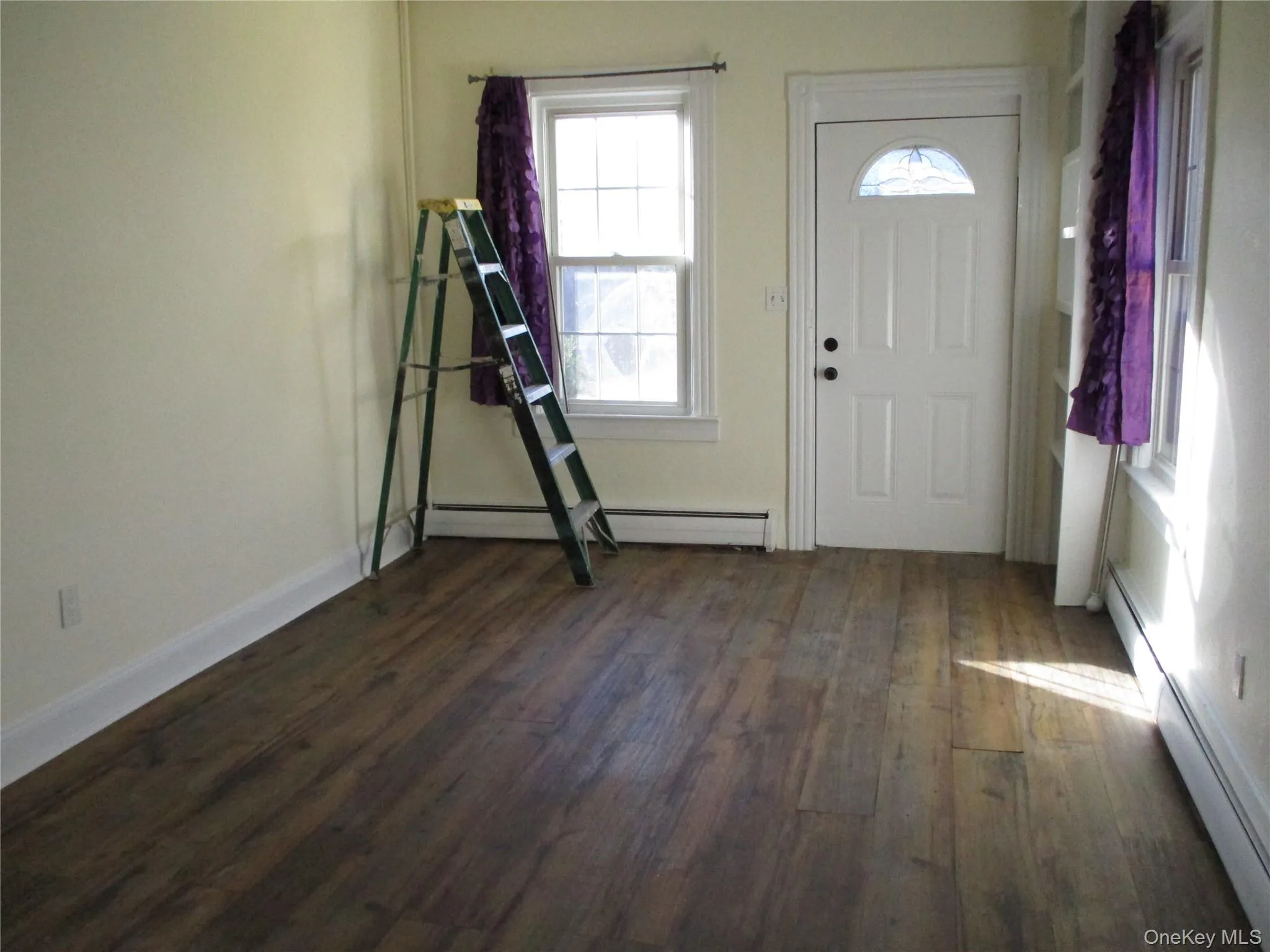 Foyer featuring dark wood-style flooring and a baseboard heating unit Foyer featuring dark wood-style flooring and a baseboard heating unit