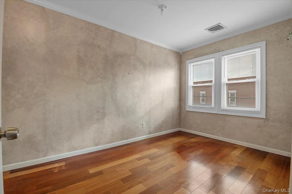 Spare room with hardwood / wood-style flooring and ornamental molding Spare room with hardwood / wood-style flooring and ornamental molding