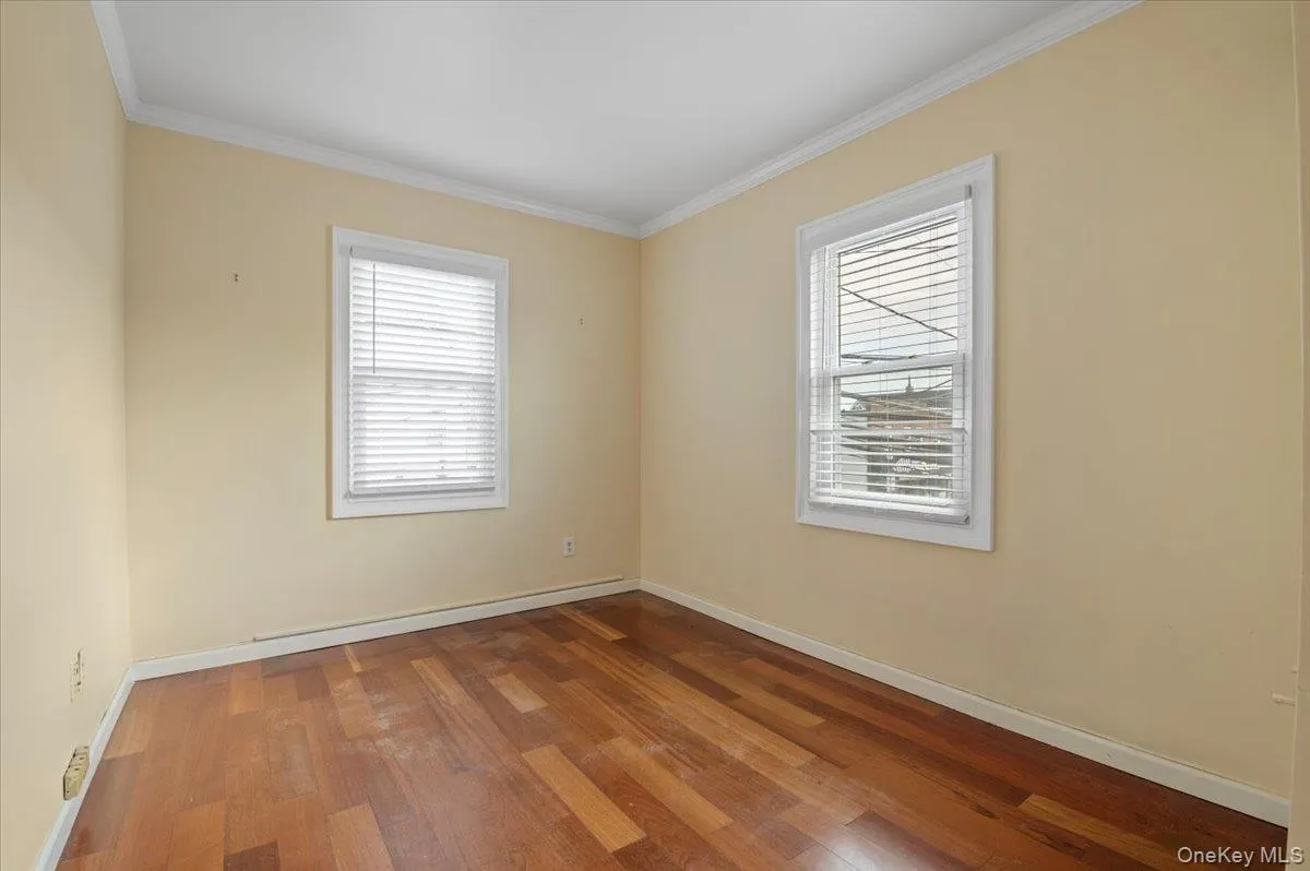 Spare room with wood finished floors, plenty of natural light, and ornamental molding Spare room with wood finished floors, plenty of natural light, and ornamental molding