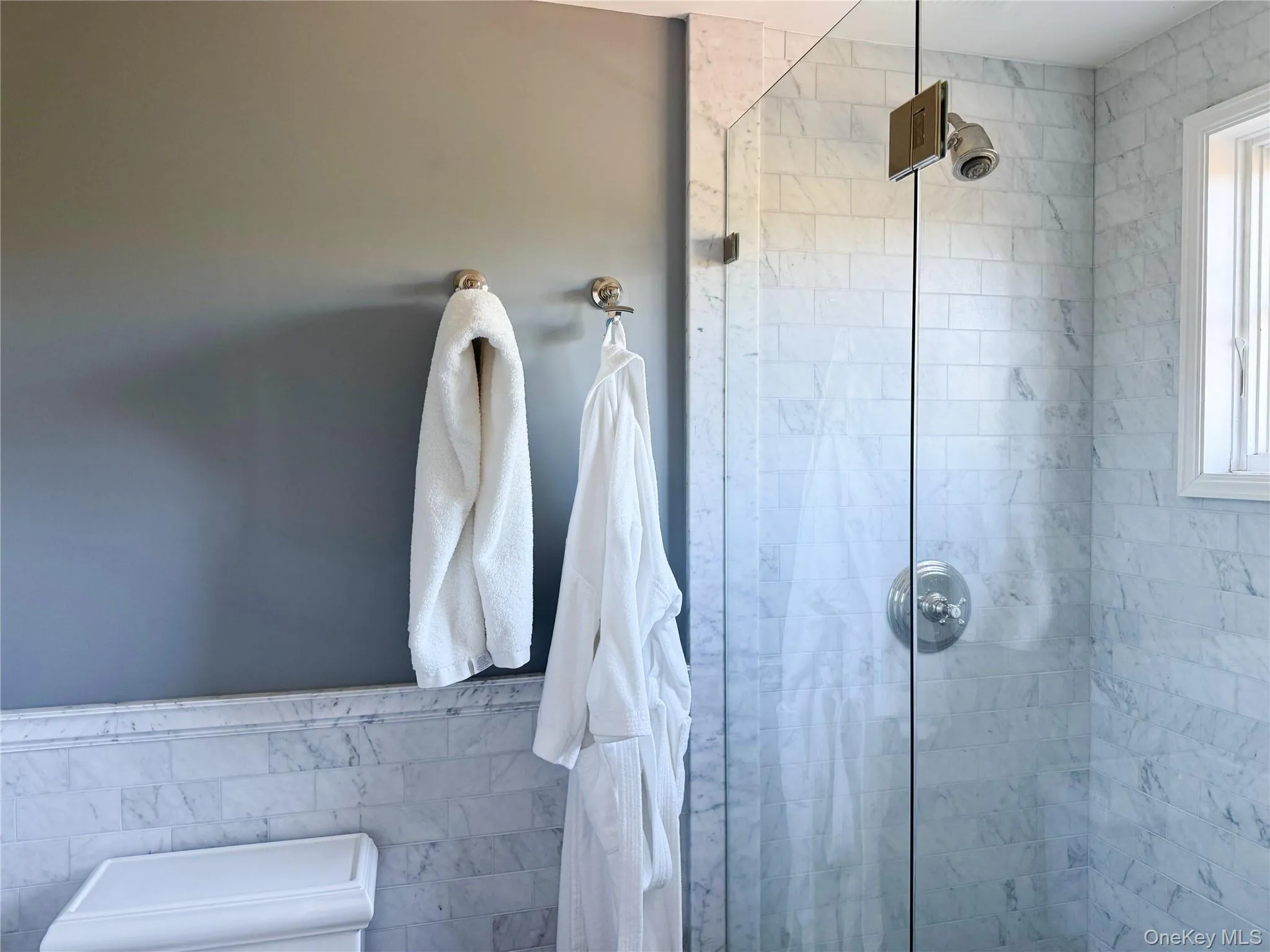 Full bath featuring a stall shower, tile walls, and wainscoting Full bath featuring a stall shower, tile walls, and wainscoting