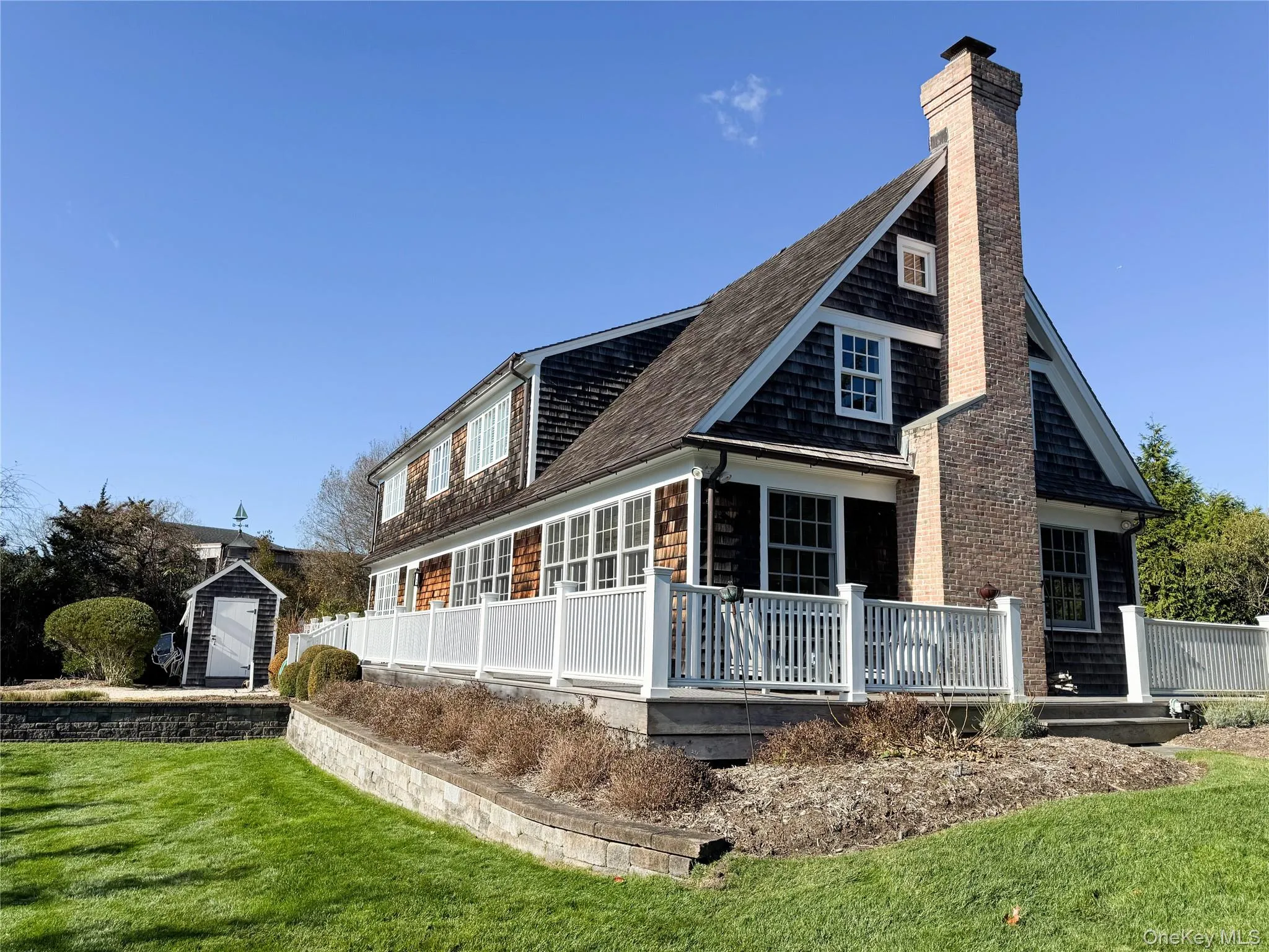 Side view of property featuring a yard, a shingled roof, a chimney, a deck, and a storage unit Side view of property featuring a yard, a shingled roof, a chimney, a deck, and a storage unit