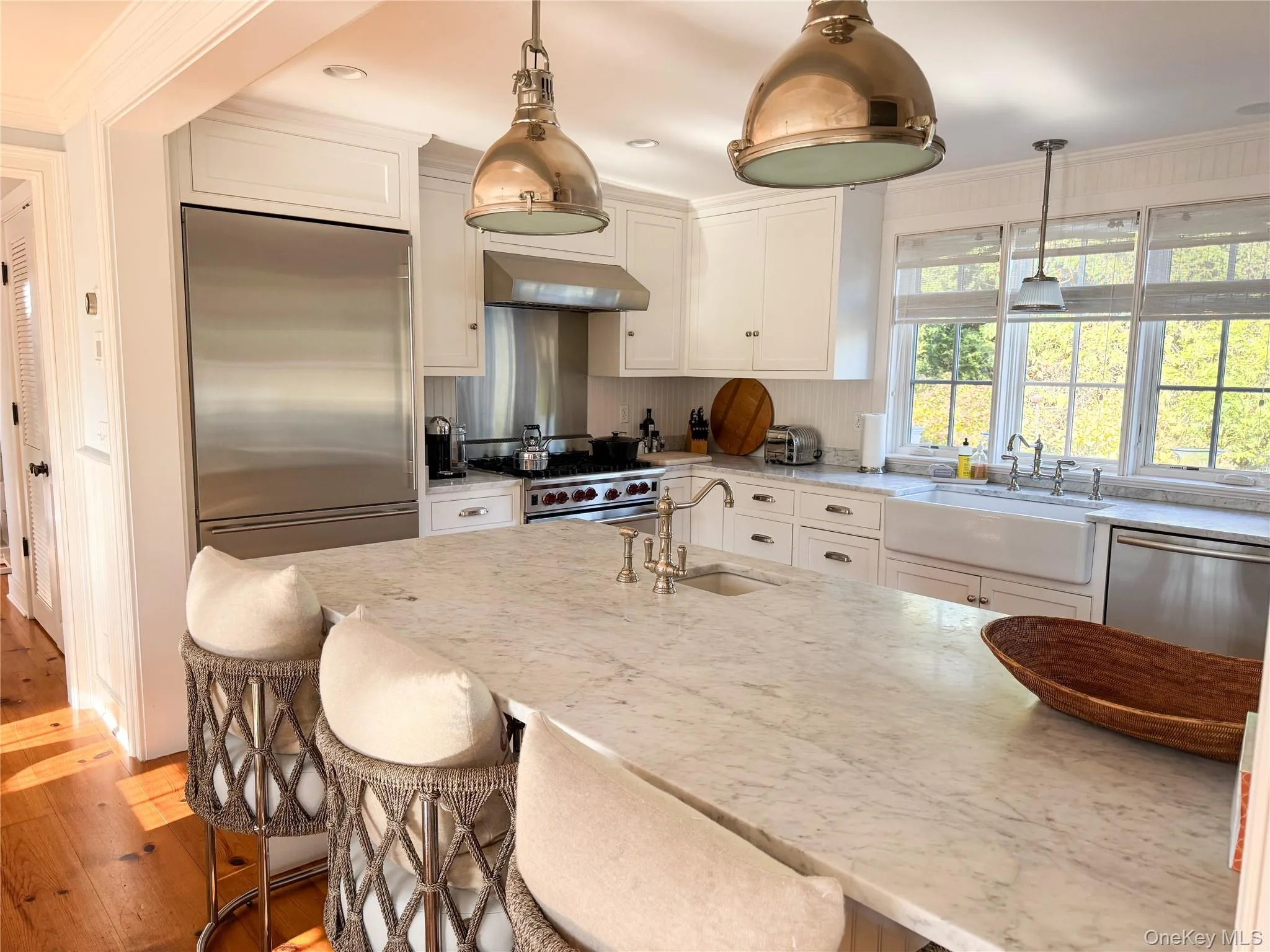 Kitchen featuring a kitchen bar, light stone countertops, crown molding, stainless steel appliances, and hanging light fixtures Kitchen featuring a kitchen bar, light stone countertops, crown molding, stainless steel appliances, and hanging light fixtures