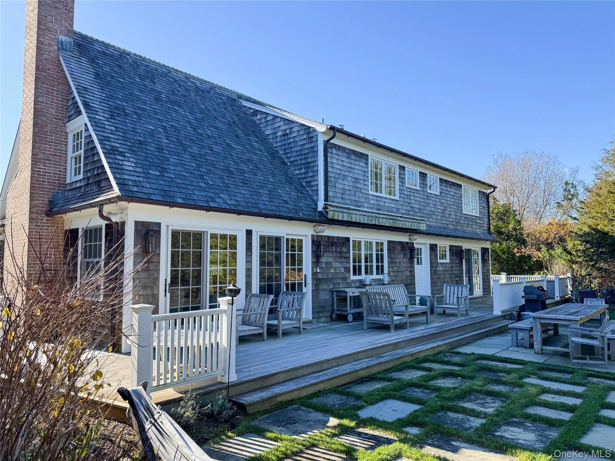 Rear view of house featuring a deck, a chimney, outdoor dining space, and roof with shingles Rear view of house featuring a deck, a chimney, outdoor dining space, and roof with shingles