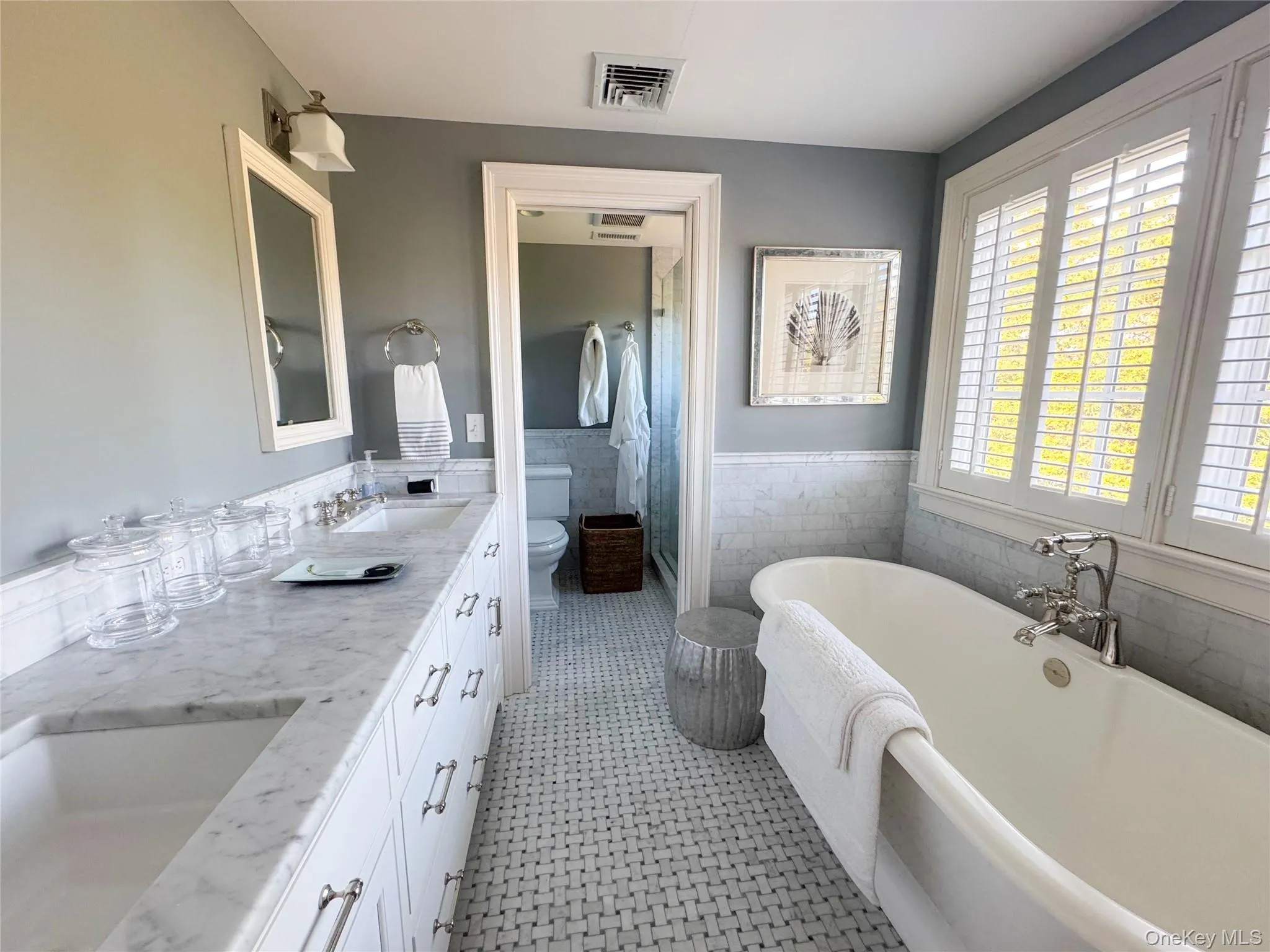 Bathroom with double vanity, a freestanding bath, a wainscoted wall, tile walls, and a stall shower Bathroom with double vanity, a freestanding bath, a wainscoted wall, tile walls, and a stall shower