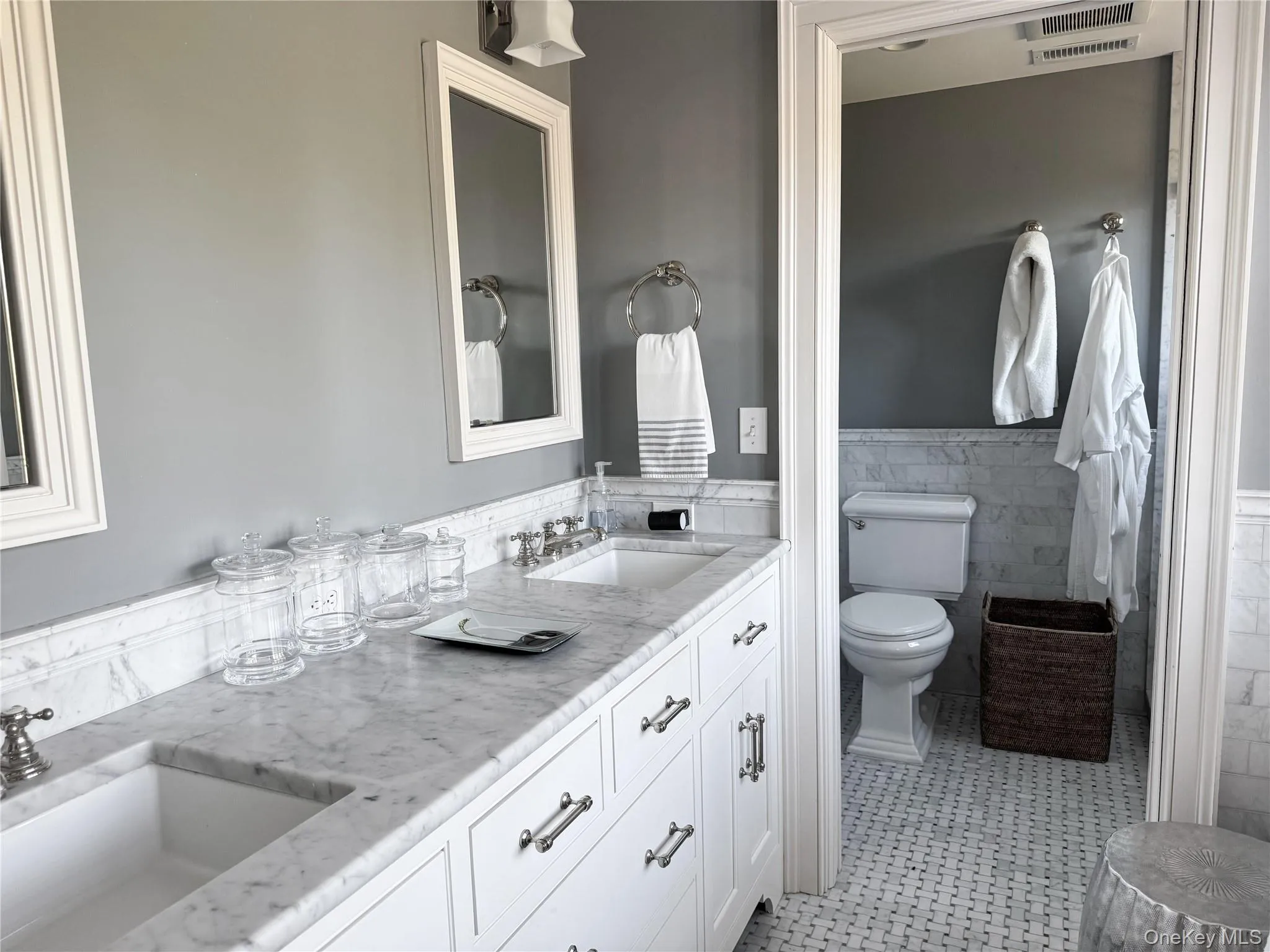 Bathroom with double vanity, wainscoting, and tile walls Bathroom with double vanity, wainscoting, and tile walls