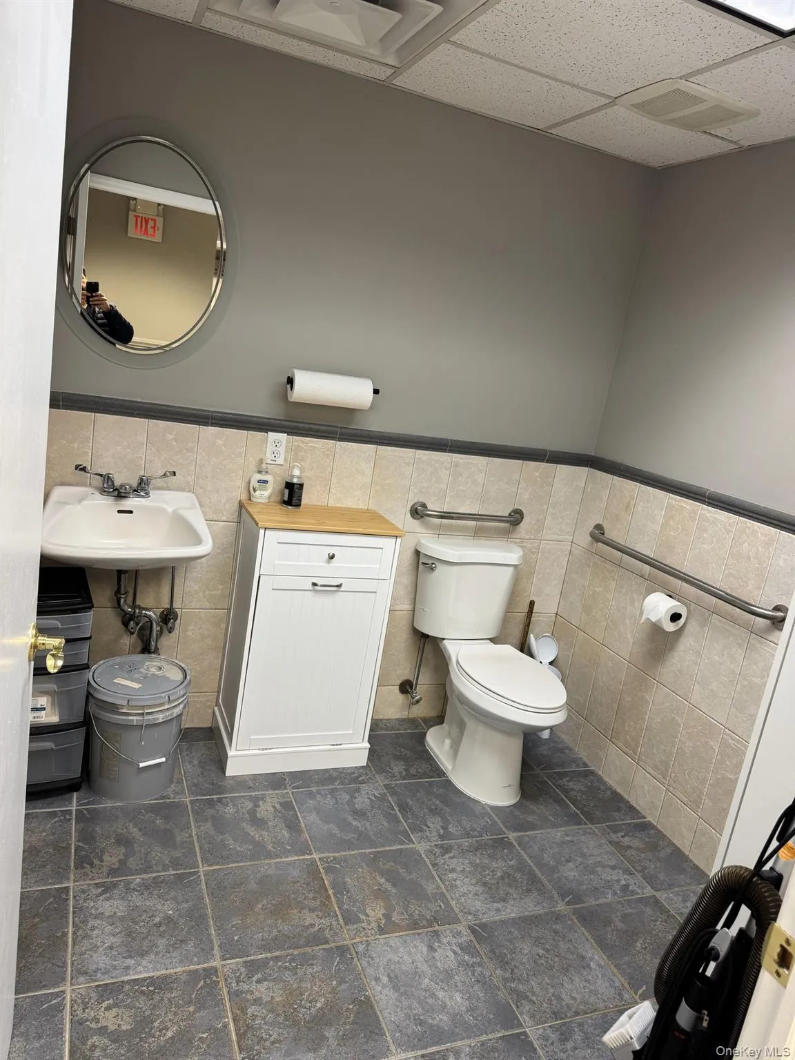 Half bathroom with wainscoting, tile walls, and a drop ceiling Half bathroom with wainscoting, tile walls, and a drop ceiling