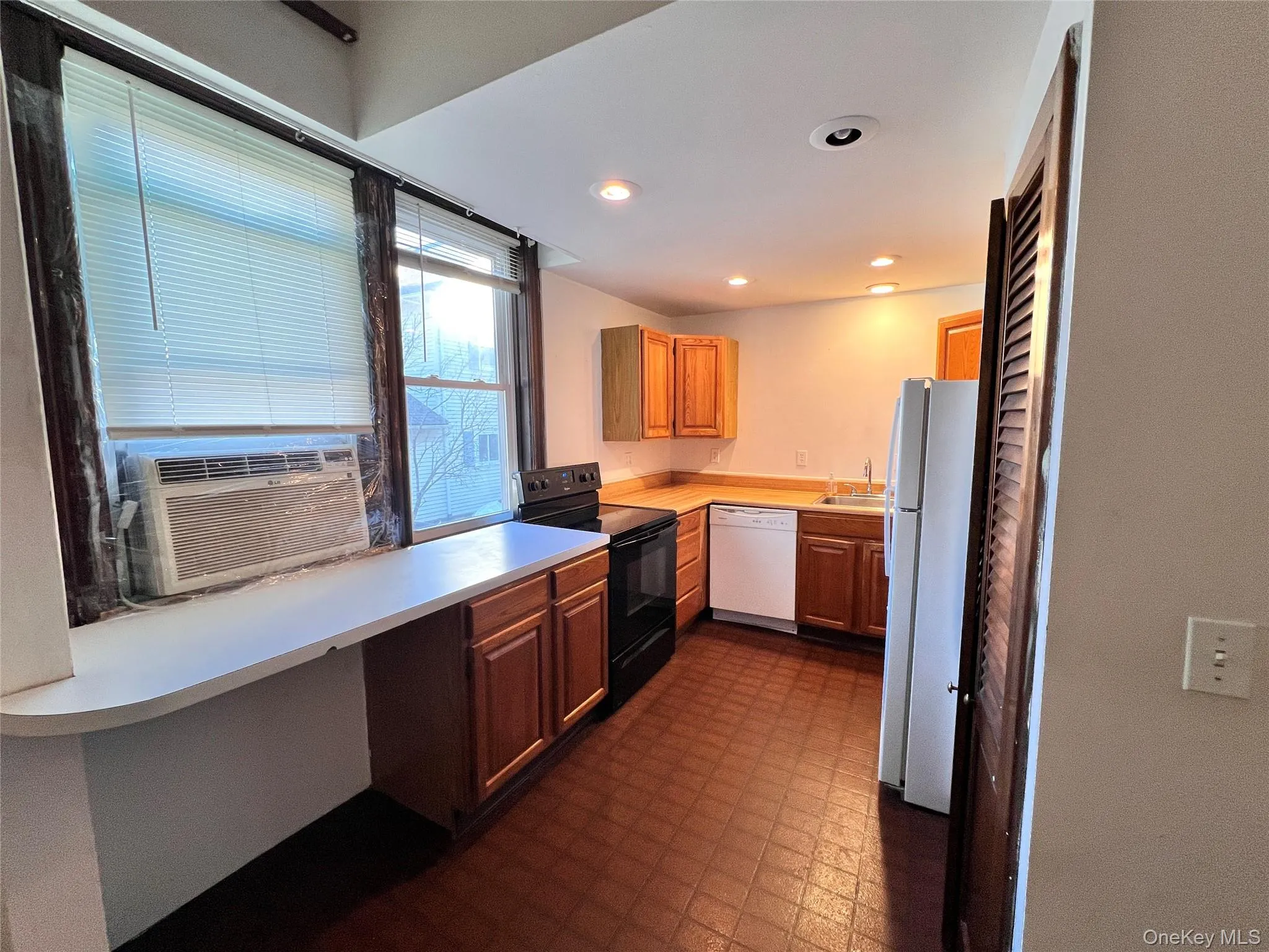 Kitchen featuring white appliances, dark flooring, light countertops, recessed lighting, and cooling unit Kitchen featuring white appliances, dark flooring, light countertops, recessed lighting, and cooling unit