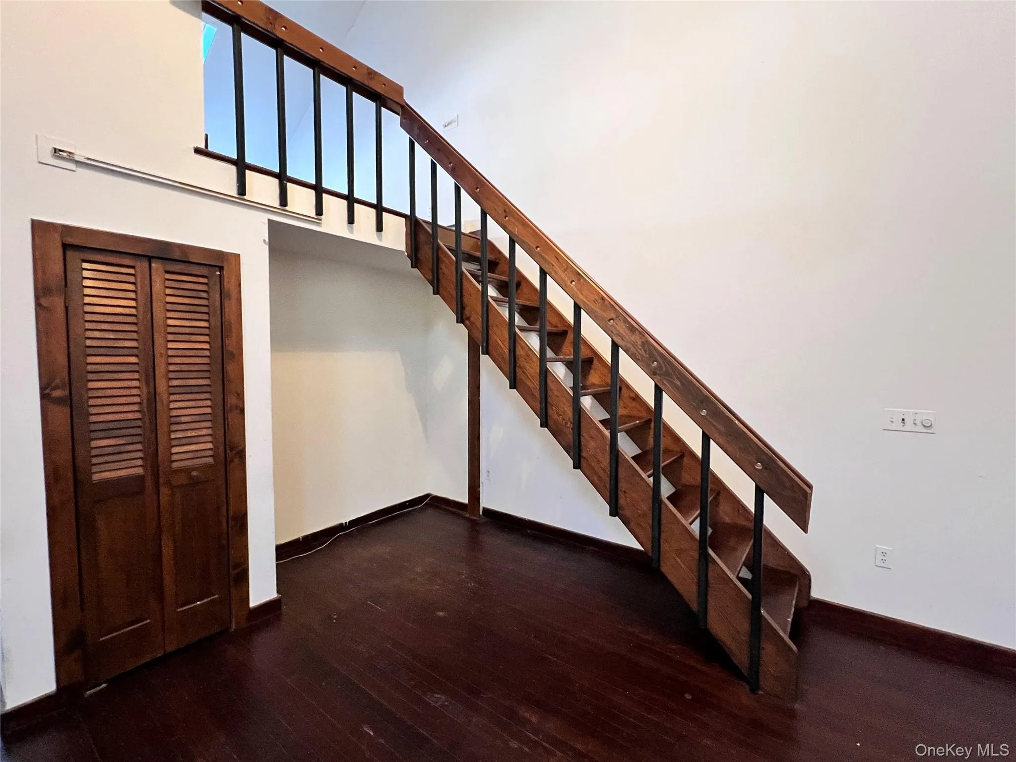 Staircase with a towering ceiling and wood-type flooring Staircase with a towering ceiling and wood-type flooring