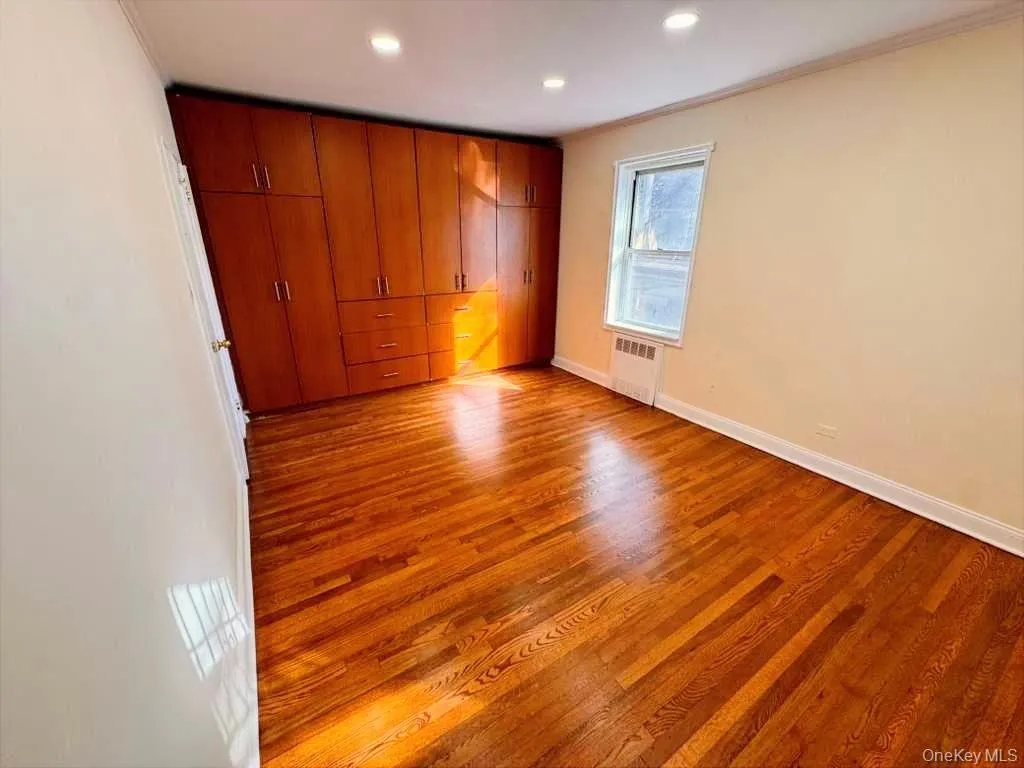 Unfurnished bedroom with light wood-style flooring, crown molding, radiator, and recessed lighting Unfurnished bedroom with light wood-style flooring, crown molding, radiator, and recessed lighting