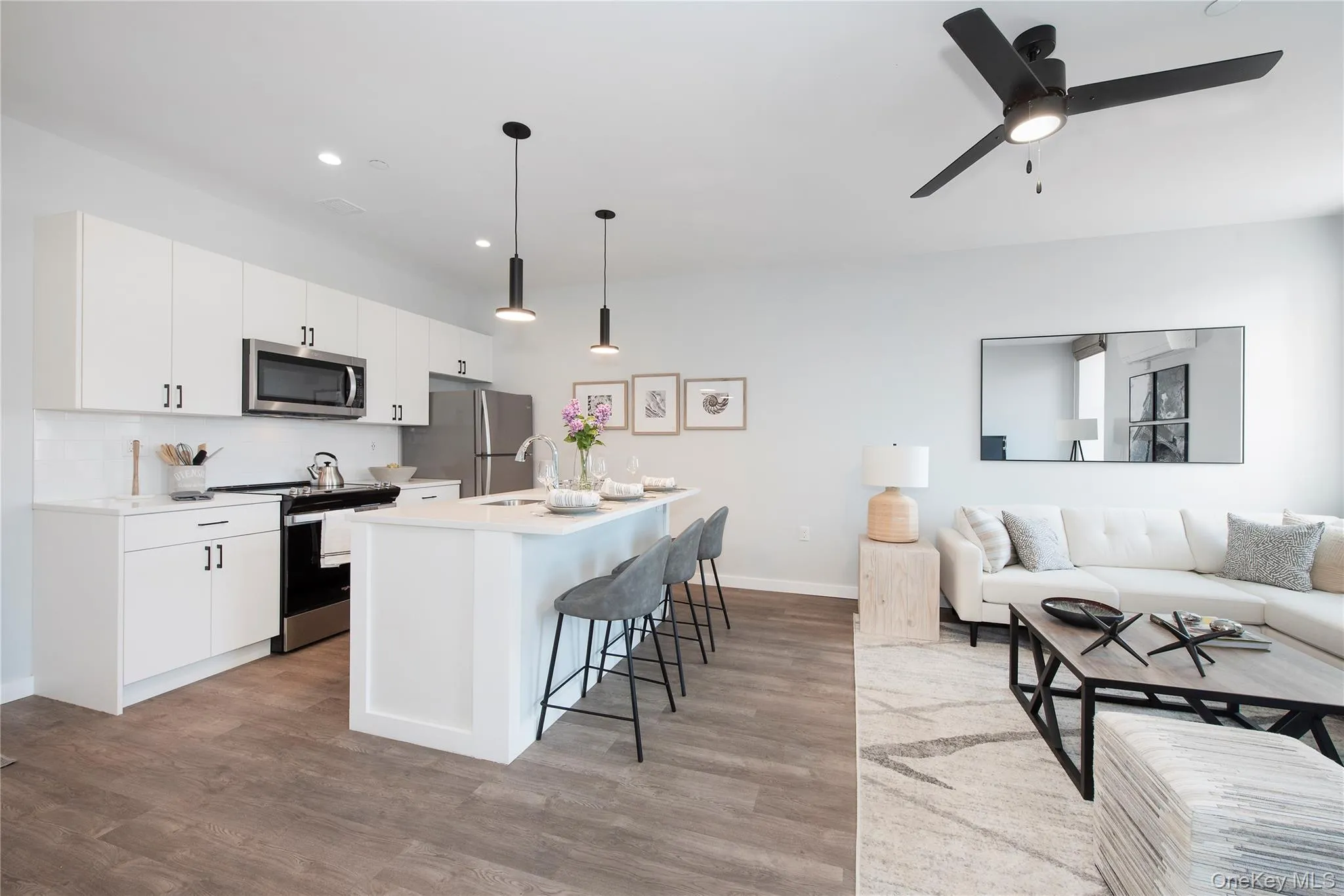 Kitchen with open floor plan, stainless steel appliances, hanging light fixtures, a kitchen bar, and a kitchen island with sink Kitchen with open floor plan, stainless steel appliances, hanging light fixtures, a kitchen bar, and a kitchen island with sink