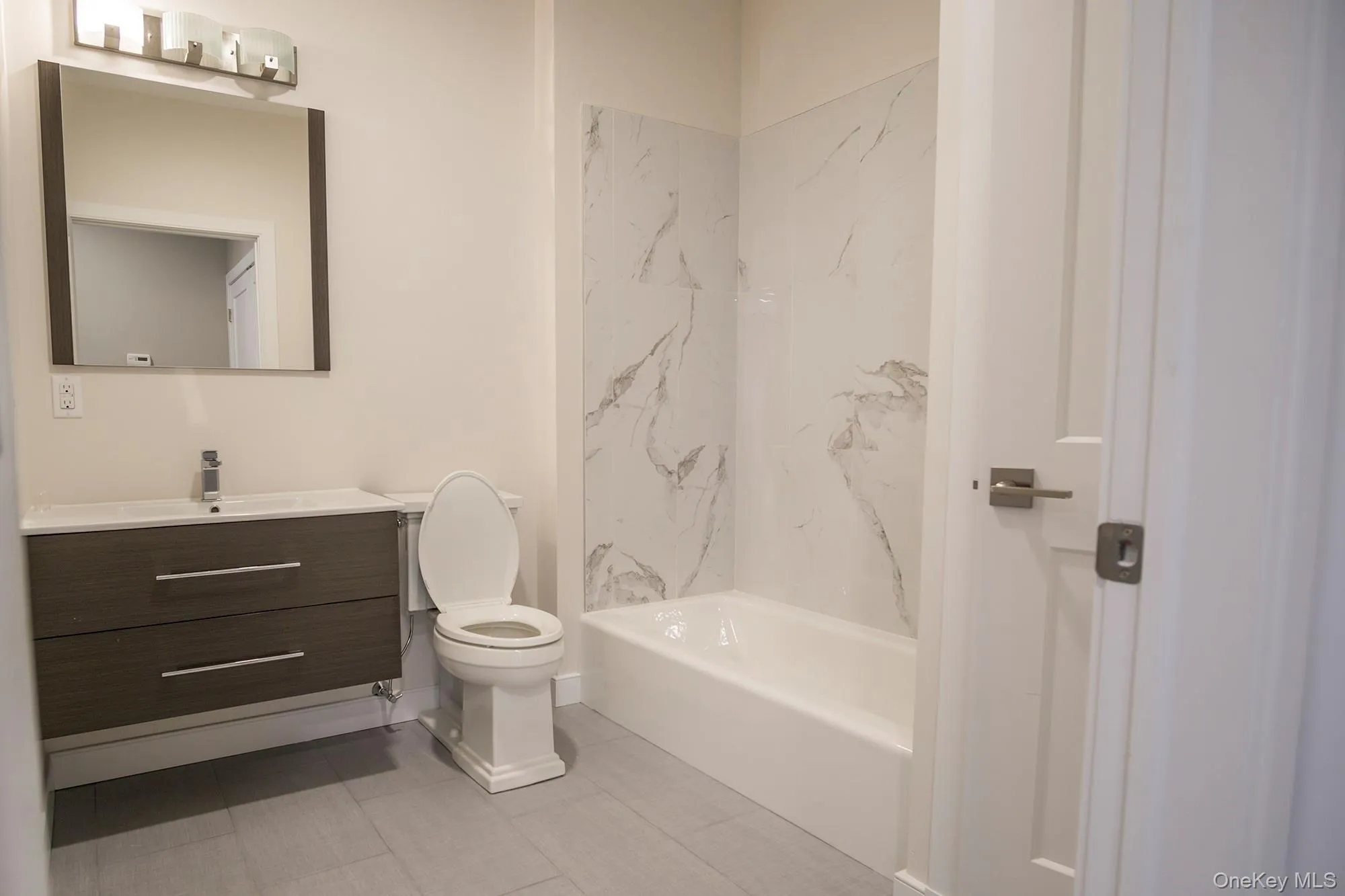 Bathroom with vanity, washtub / shower combination, and light tile patterned floors Bathroom with vanity, washtub / shower combination, and light tile patterned floors