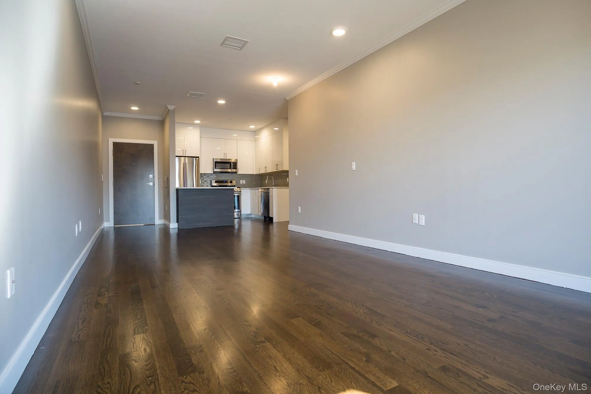 Unfurnished living room featuring recessed lighting, ornamental molding, and dark wood-style flooring Unfurnished living room featuring recessed lighting, ornamental molding, and dark wood-style flooring