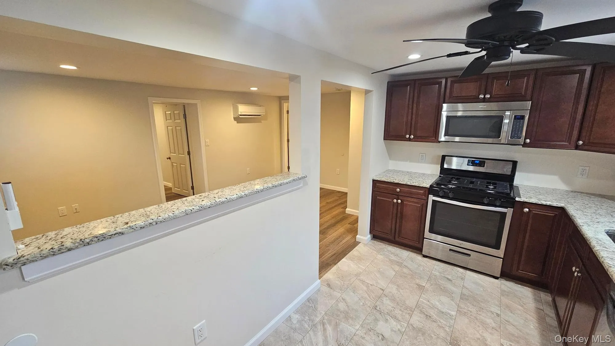 Kitchen featuring appliances with stainless steel finishes, dark brown cabinets, a ceiling fan, light stone counters, and recessed lighting Kitchen featuring appliances with stainless steel finishes, dark brown cabinets, a ceiling fan, light stone counters, and recessed lighting