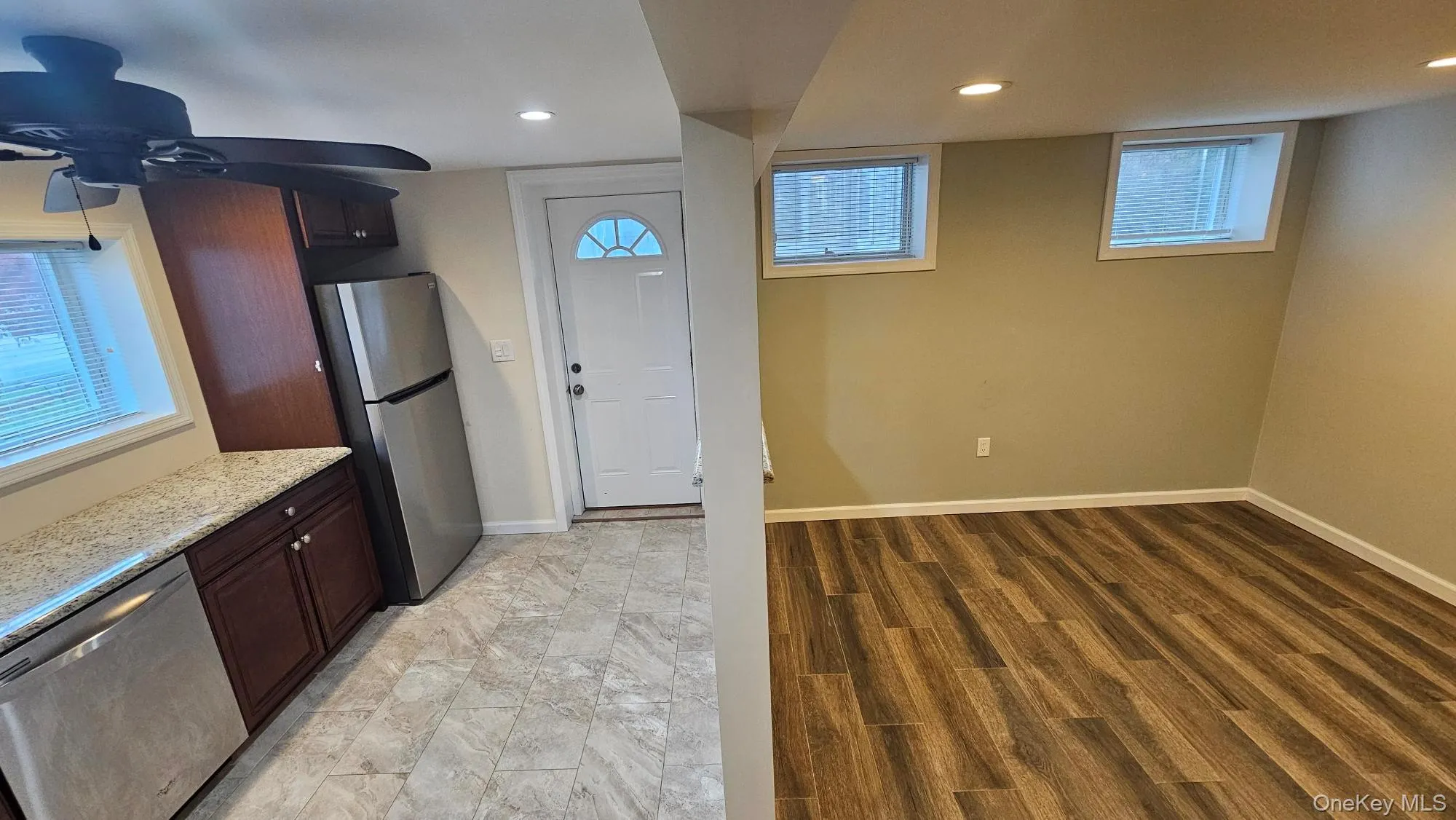 Kitchen featuring appliances with stainless steel finishes, light stone countertops, dark brown cabinets, recessed lighting, and light wood-style flooring Kitchen featuring appliances with stainless steel finishes, light stone countertops, dark brown cabinets, recessed lighting, and light wood-style flooring