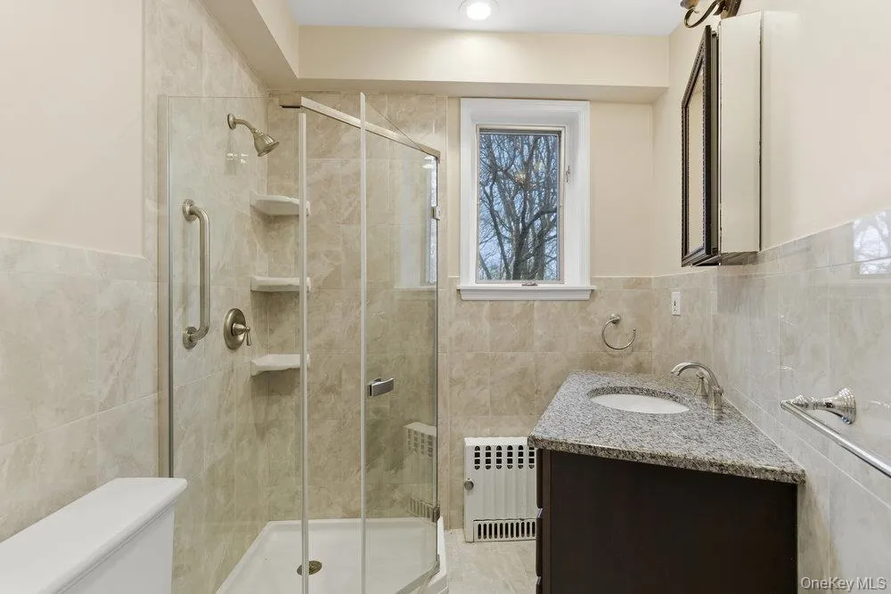 Full bathroom featuring ceramic tile walls and floor, vanity & shower Full bathroom featuring ceramic tile walls and floor, vanity & shower