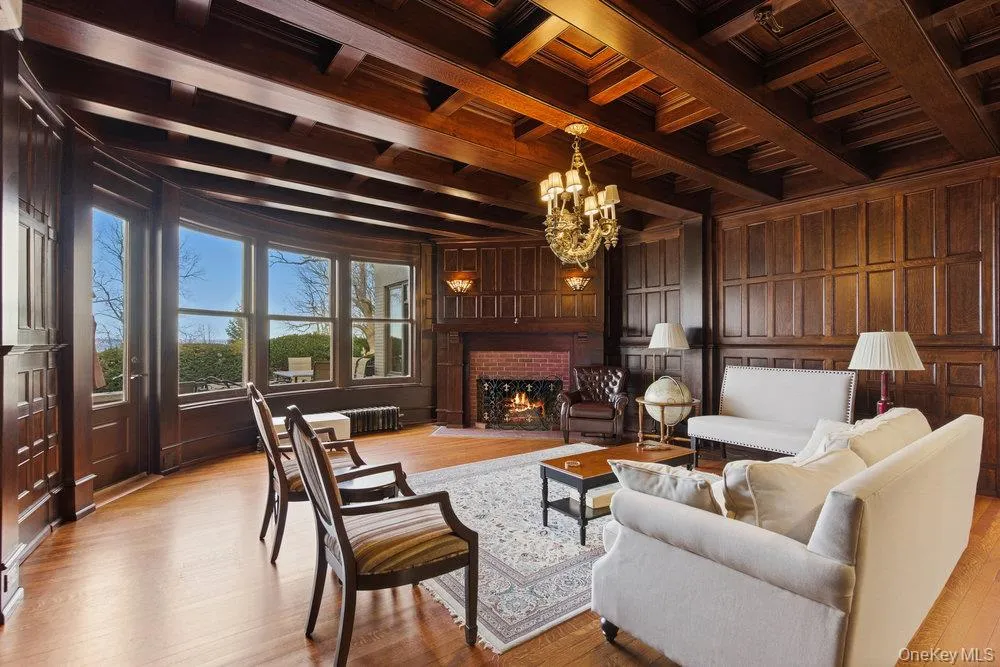 Parlor with a wood ceiling with exposed beams, chandelier, and brick fireplace, original oak flooring Parlor with a wood ceiling with exposed beams, chandelier, and brick fireplace, original oak flooring