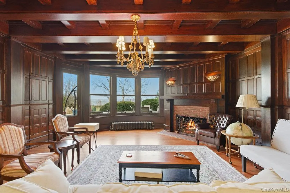 Parlor featuring original oak floors, a custom mermaid chandelier, and a brick fireplace Parlor featuring original oak floors, a custom mermaid chandelier, and a brick fireplace