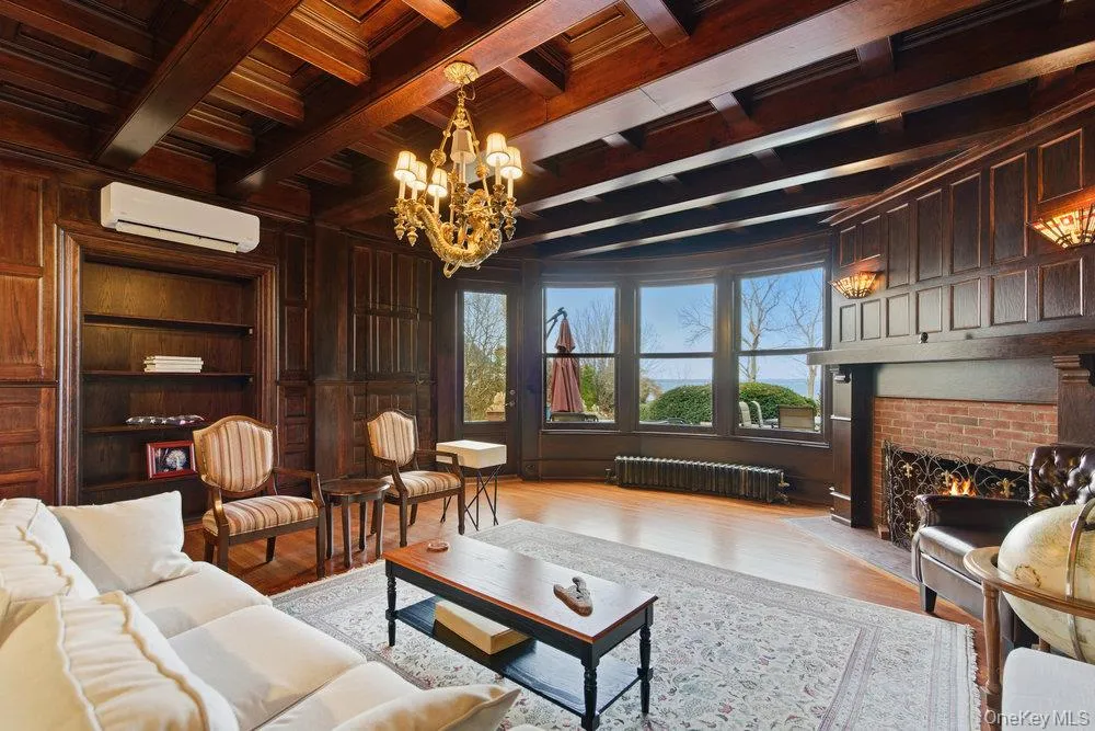 parlor featuring a fireplace, exposed beam ceiling, a custom mermaid chandelier, and original oak floors parlor featuring a fireplace, exposed beam ceiling, a custom mermaid chandelier, and original oak floors