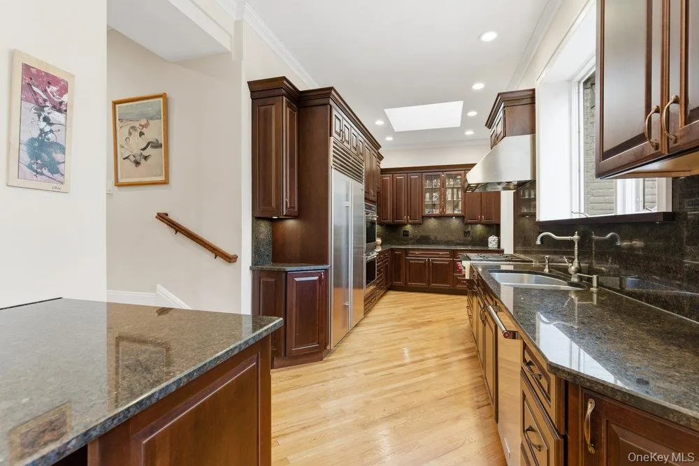 Kitchen with skylight, stone countertops, hardwood floors under cabinet range hood, and ornamental molding Kitchen with skylight, stone countertops, hardwood floors under cabinet range hood, and ornamental molding