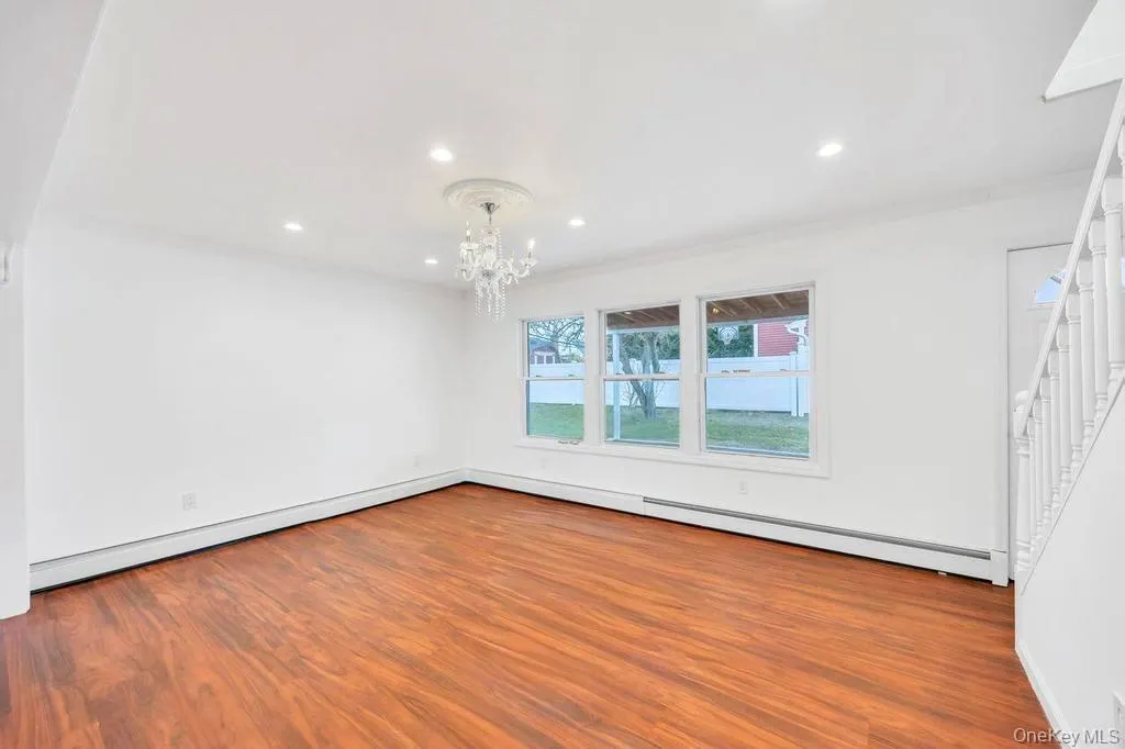 Spare room with wood finished floors, a chandelier, baseboard heating, a baseboard radiator, and crown molding Spare room with wood finished floors, a chandelier, baseboard heating, a baseboard radiator, and crown molding