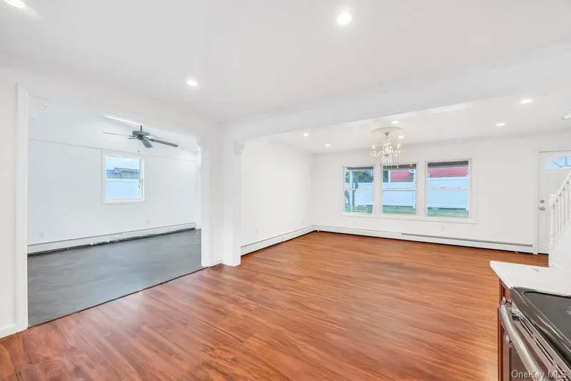Unfurnished living room with light wood-style floors, a baseboard heating unit, plenty of natural light, and recessed lighting Unfurnished living room with light wood-style floors, a baseboard heating unit, plenty of natural light, and recessed lighting