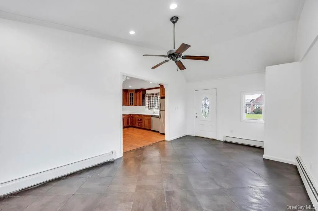 Unfurnished living room featuring baseboard heating, ornamental molding, a baseboard heating unit, recessed lighting, and vaulted ceiling Unfurnished living room featuring baseboard heating, ornamental molding, a baseboard heating unit, recessed lighting, and vaulted ceiling