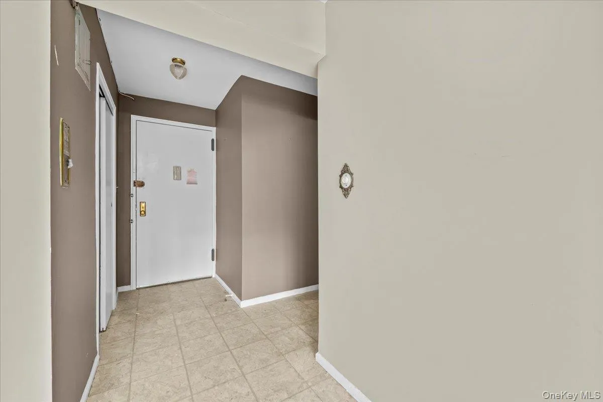 Hall featuring baseboards and light tile patterned floors Hall featuring baseboards and light tile patterned floors