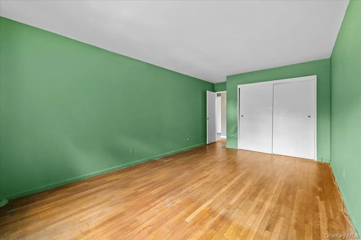 Unfurnished bedroom with a closet and hardwood / wood-style floors Unfurnished bedroom with a closet and hardwood / wood-style floors