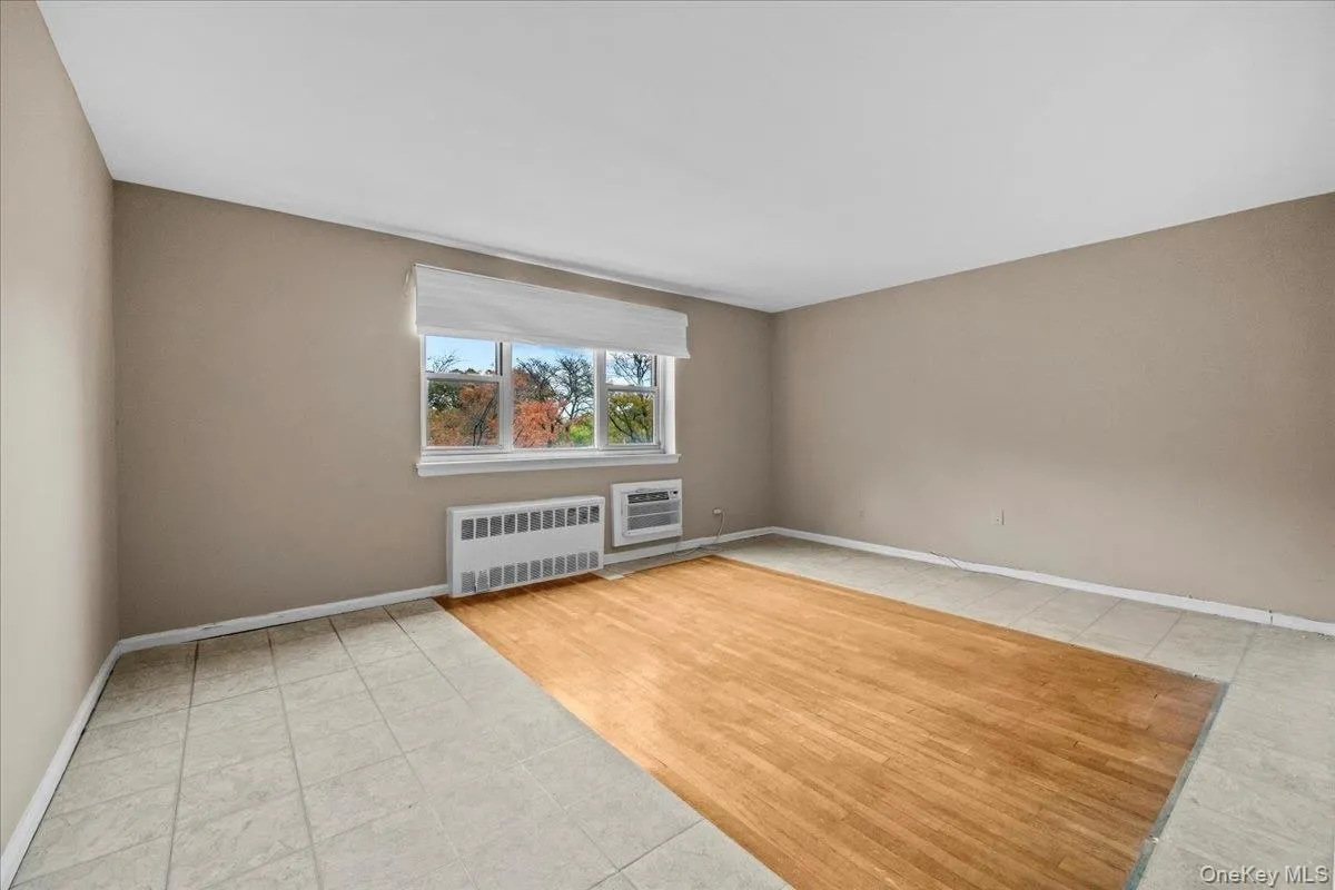 Unfurnished room featuring radiator heating unit and light tile patterned floors Unfurnished room featuring radiator heating unit and light tile patterned floors
