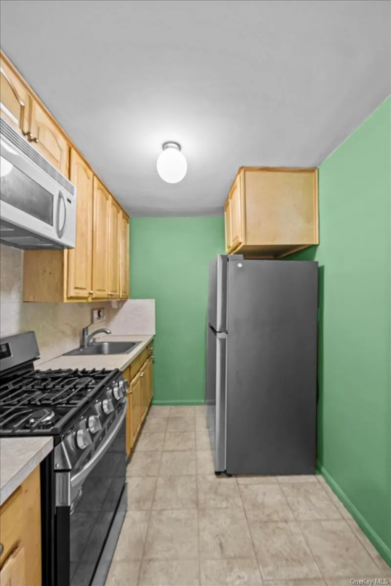 Kitchen featuring appliances with stainless steel finishes, light brown cabinets, light countertops, and decorative backsplash Kitchen featuring appliances with stainless steel finishes, light brown cabinets, light countertops, and decorative backsplash