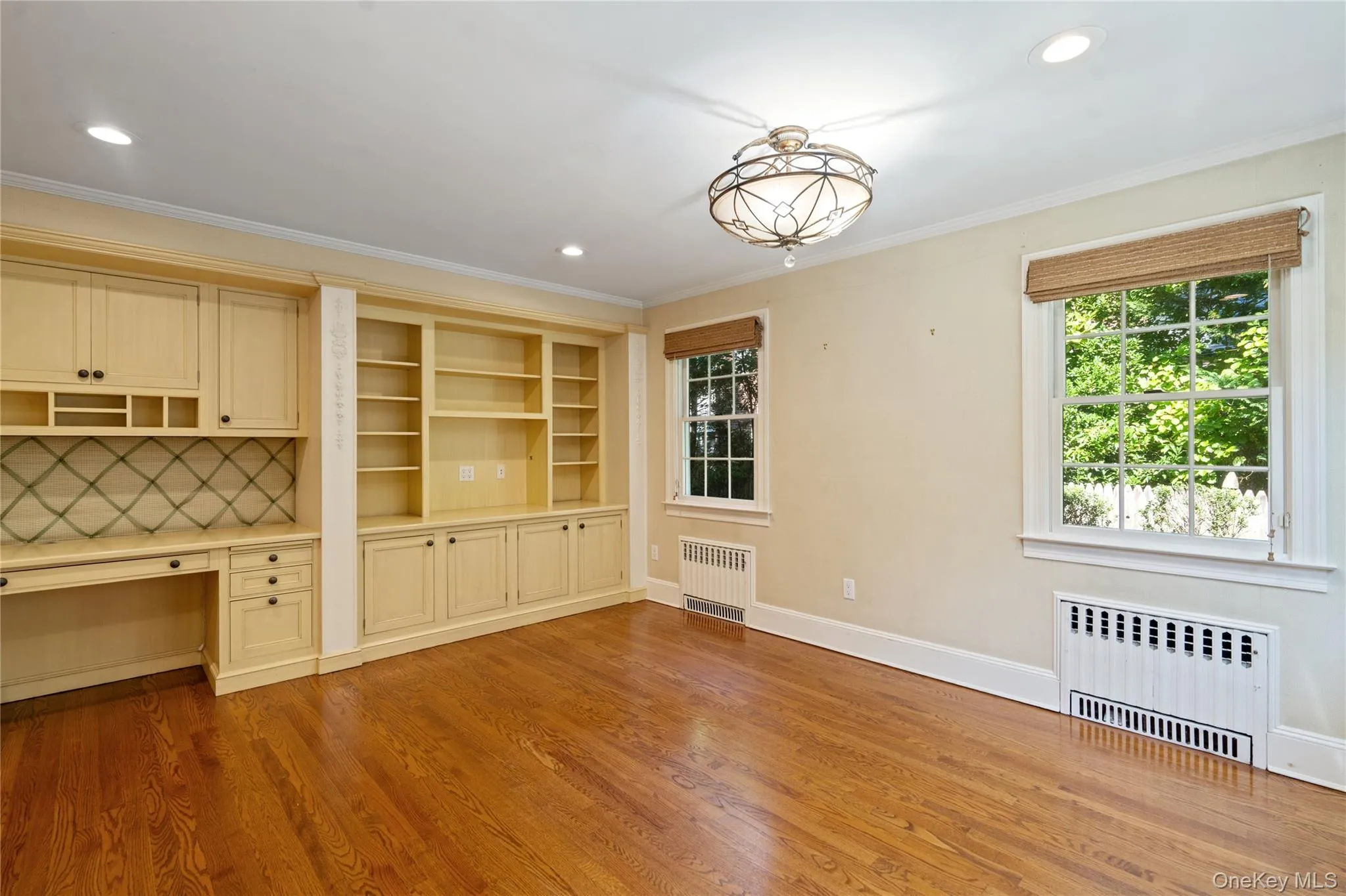 Unfurnished dining area with radiator, light wood-style floors, built in study area, ornamental molding, and recessed lighting Unfurnished dining area with radiator, light wood-style floors, built in study area, ornamental molding, and recessed lighting