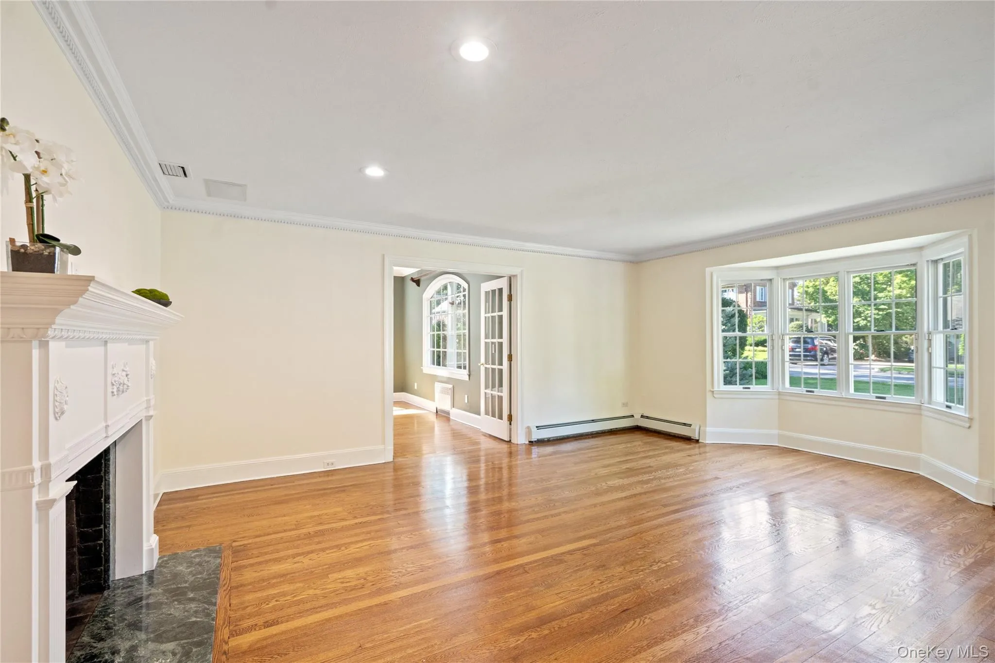 Unfurnished living room with light wood-style floors, ornamental molding, a fireplace with flush hearth, healthy amount of natural light, and recessed lighting Unfurnished living room with light wood-style floors, ornamental molding, a fireplace with flush hearth, healthy amount of natural light, and recessed lighting