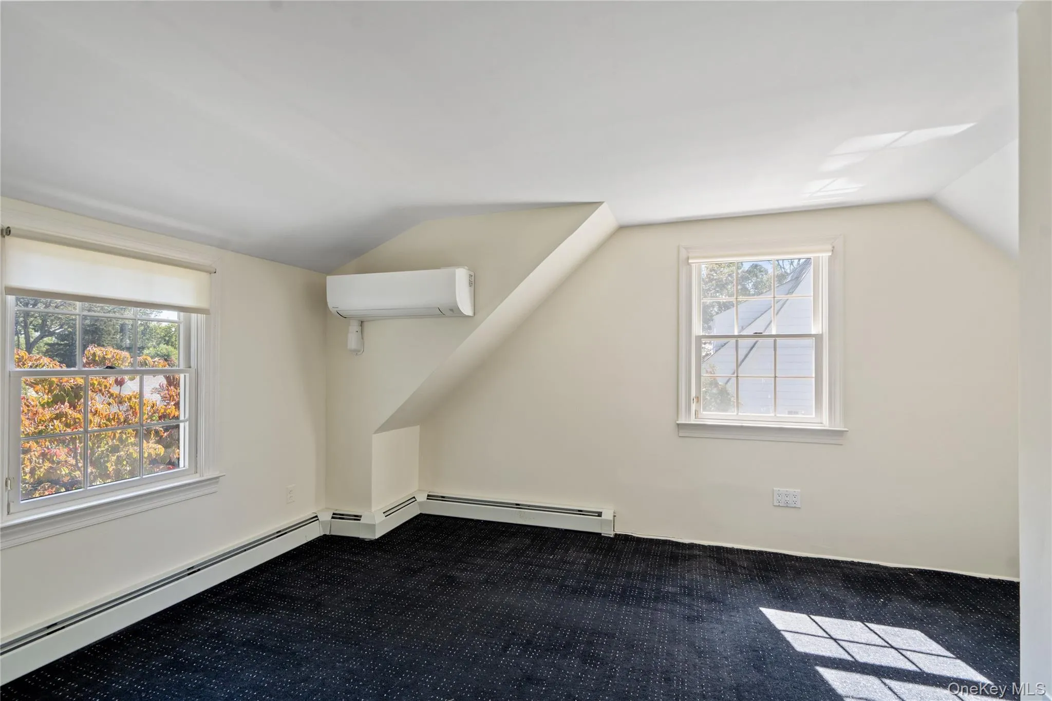 Additional living space with vaulted ceiling, an AC wall unit, dark carpet, and a baseboard radiator Additional living space with vaulted ceiling, an AC wall unit, dark carpet, and a baseboard radiator