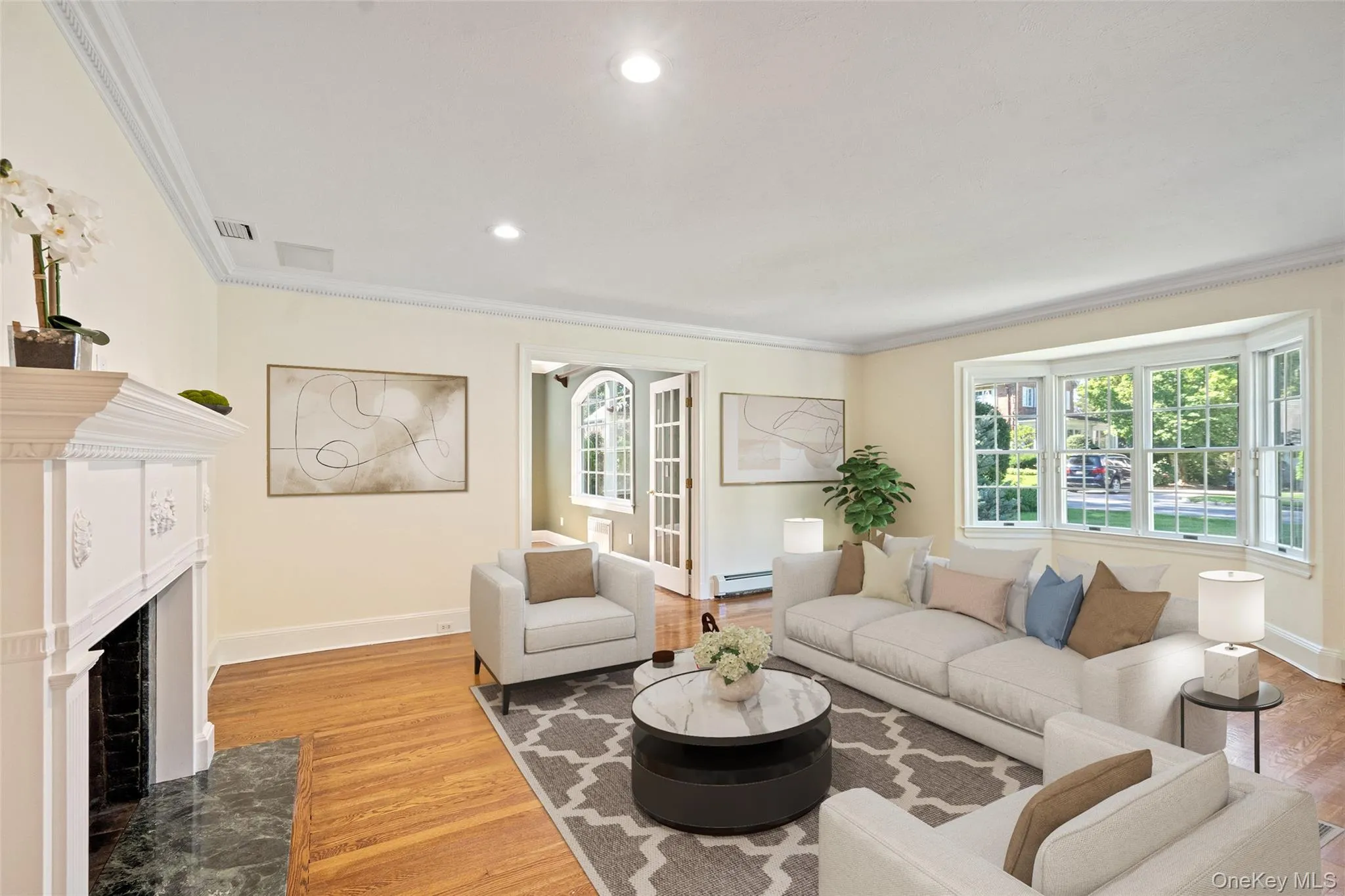 Living area featuring ornamental molding, a fireplace with flush hearth, healthy amount of natural light, recessed lighting, and light wood-style flooring Living area featuring ornamental molding, a fireplace with flush hearth, healthy amount of natural light, recessed lighting, and light wood-style flooring