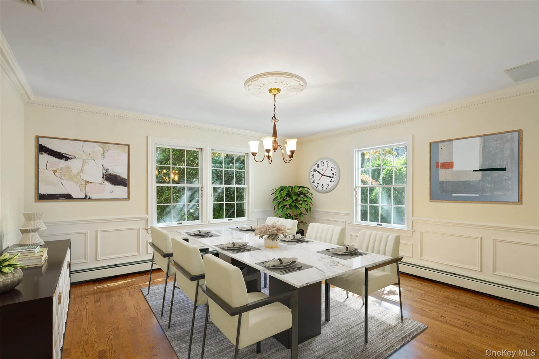 Dining room featuring wainscoting, a decorative wall, plenty of natural light, wood finished floors, and baseboard heating Dining room featuring wainscoting, a decorative wall, plenty of natural light, wood finished floors, and baseboard heating