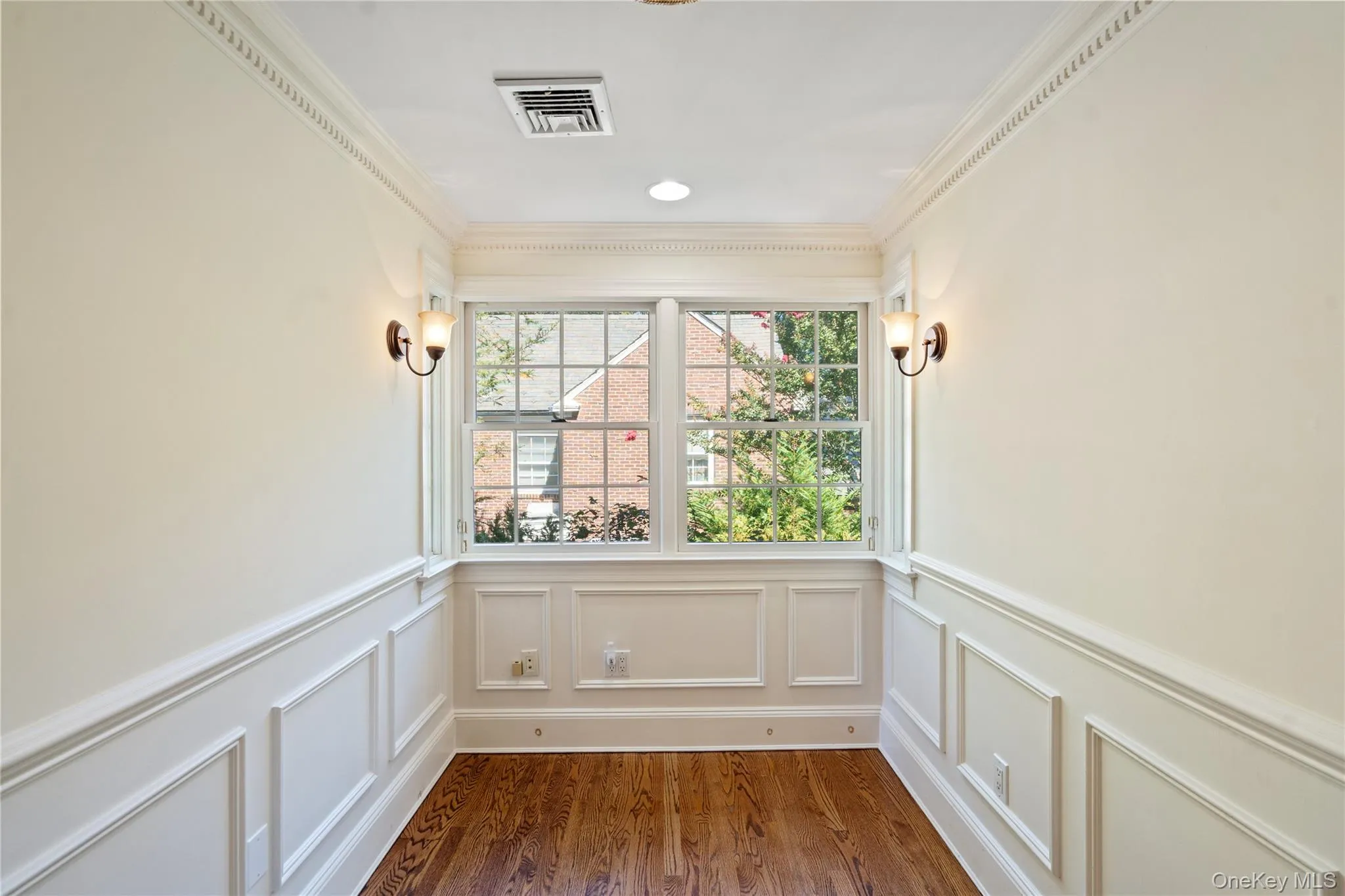 Unfurnished sunroom with ornamental molding, wood finished floors, and a wainscoted wall Unfurnished sunroom with ornamental molding, wood finished floors, and a wainscoted wall