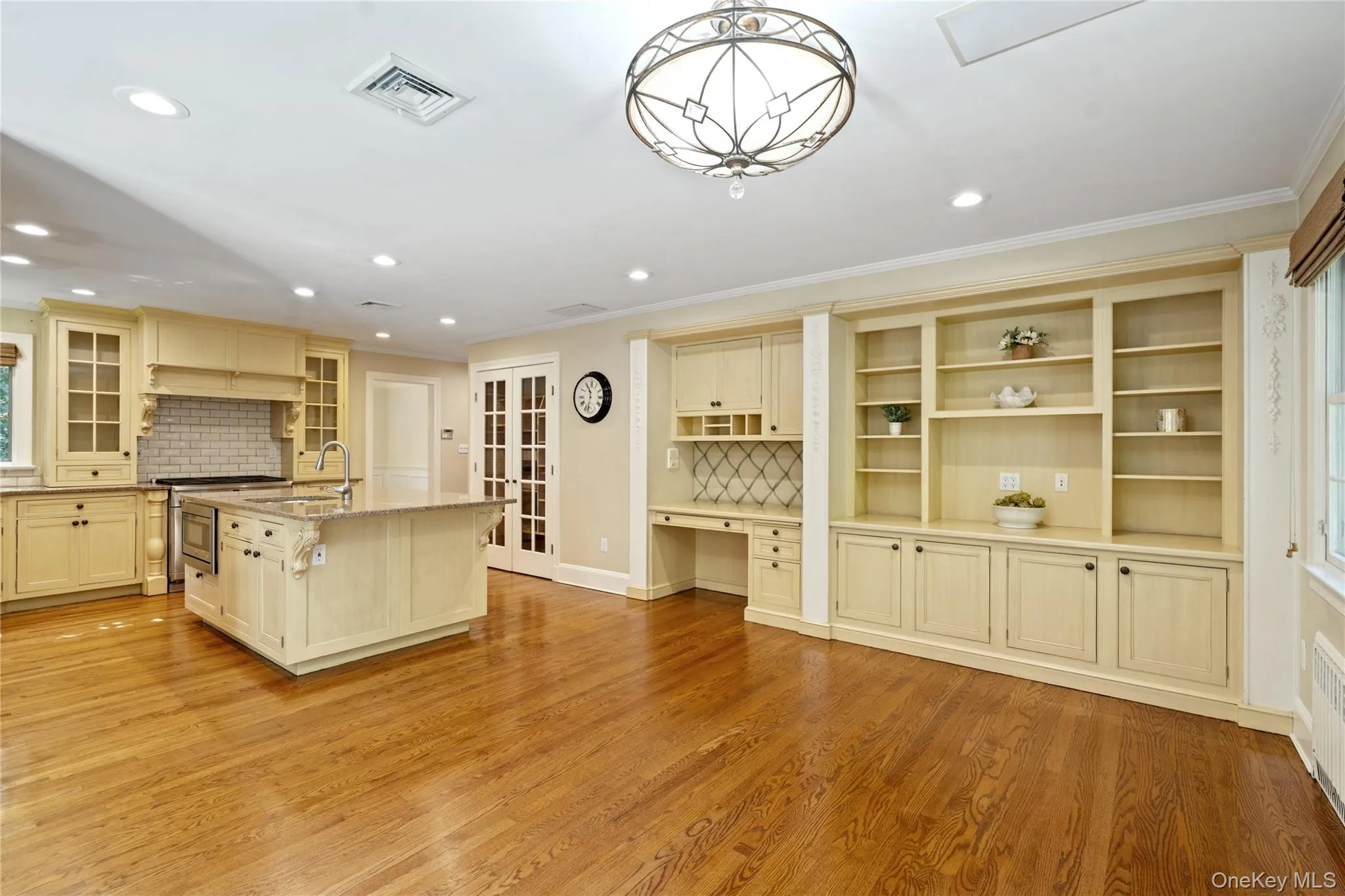 Kitchen with built in study area, light stone countertops, a kitchen island with sink, light wood-style floors, and tasteful backsplash Kitchen with built in study area, light stone countertops, a kitchen island with sink, light wood-style floors, and tasteful backsplash