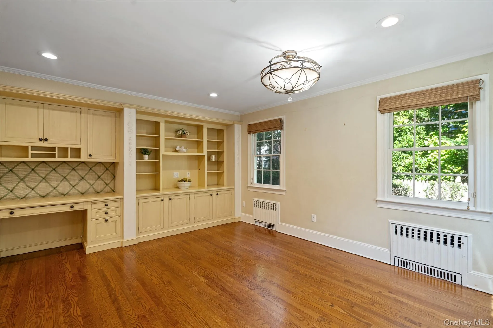Unfurnished dining area with radiator, dark wood-style floors, crown molding, recessed lighting, and built in study area Unfurnished dining area with radiator, dark wood-style floors, crown molding, recessed lighting, and built in study area