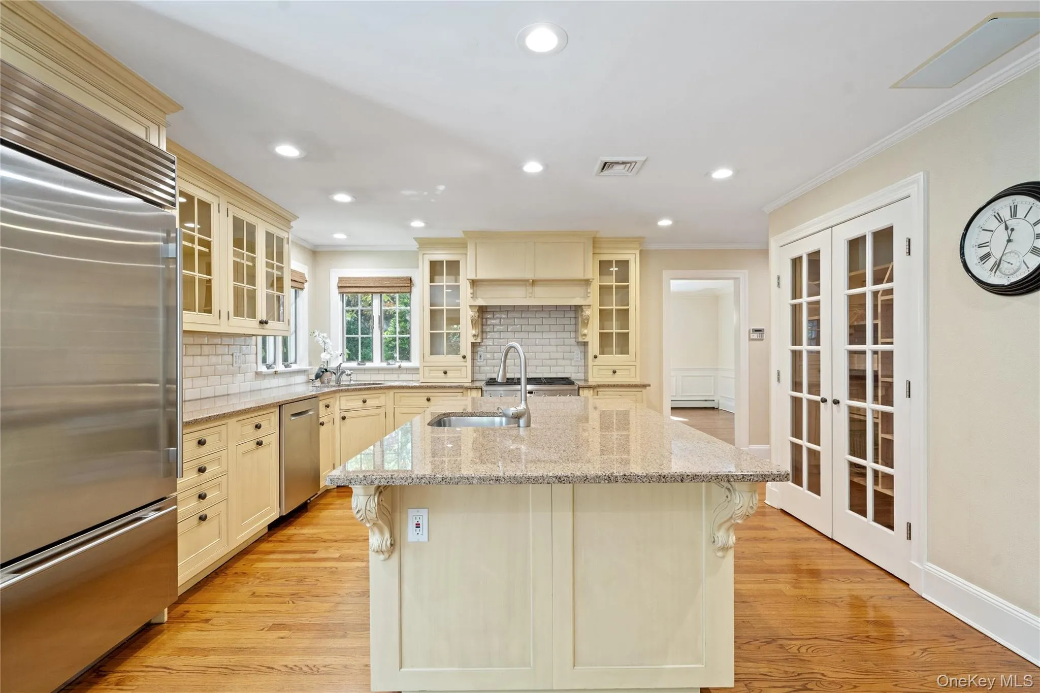 Kitchen featuring appliances with stainless steel finishes, glass insert cabinets, light stone counters, decorative backsplash, and recessed lighting Kitchen featuring appliances with stainless steel finishes, glass insert cabinets, light stone counters, decorative backsplash, and recessed lighting