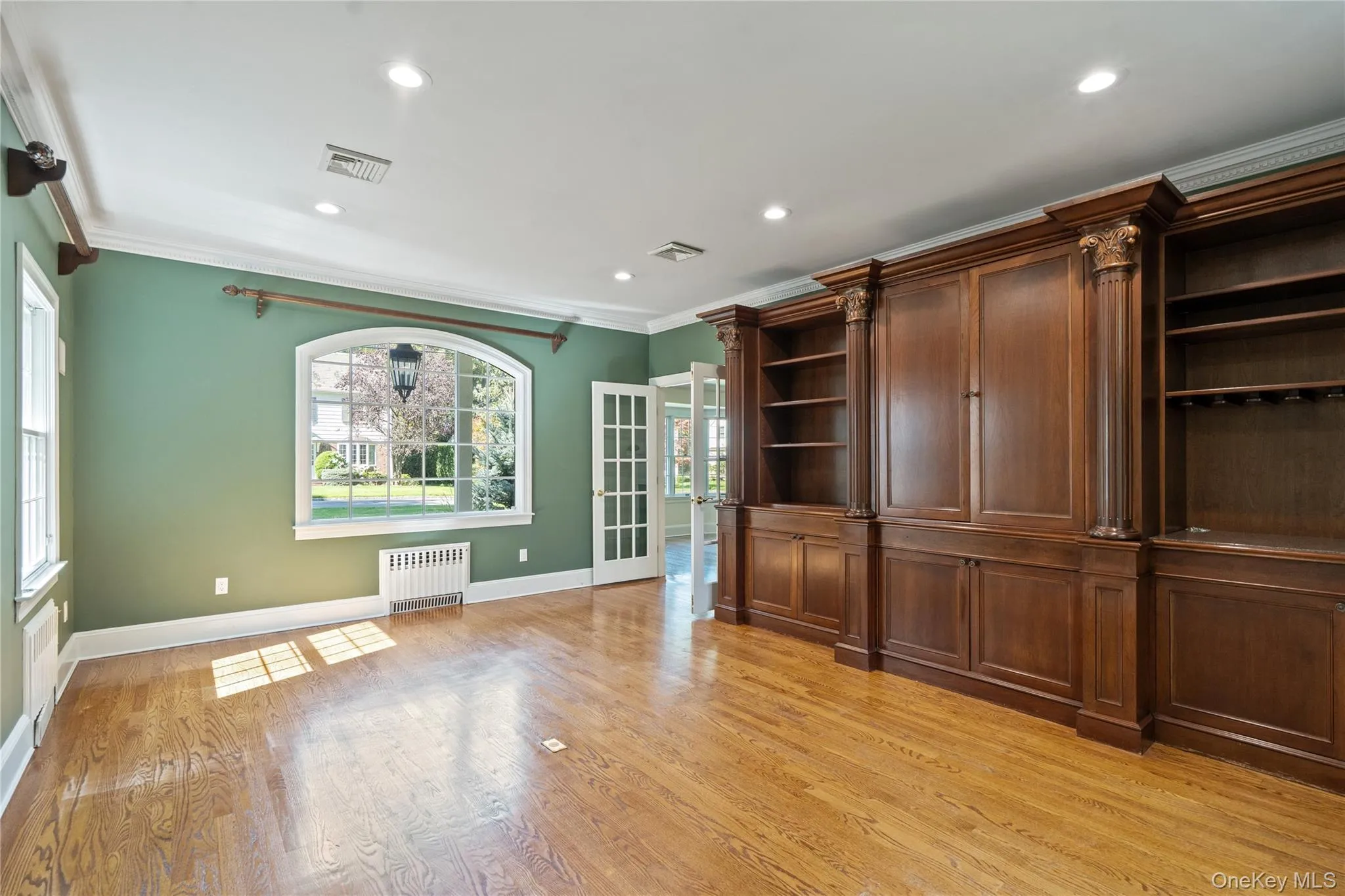 Unfurnished living room with light wood-style floors, radiator, crown molding, and recessed lighting Unfurnished living room with light wood-style floors, radiator, crown molding, and recessed lighting