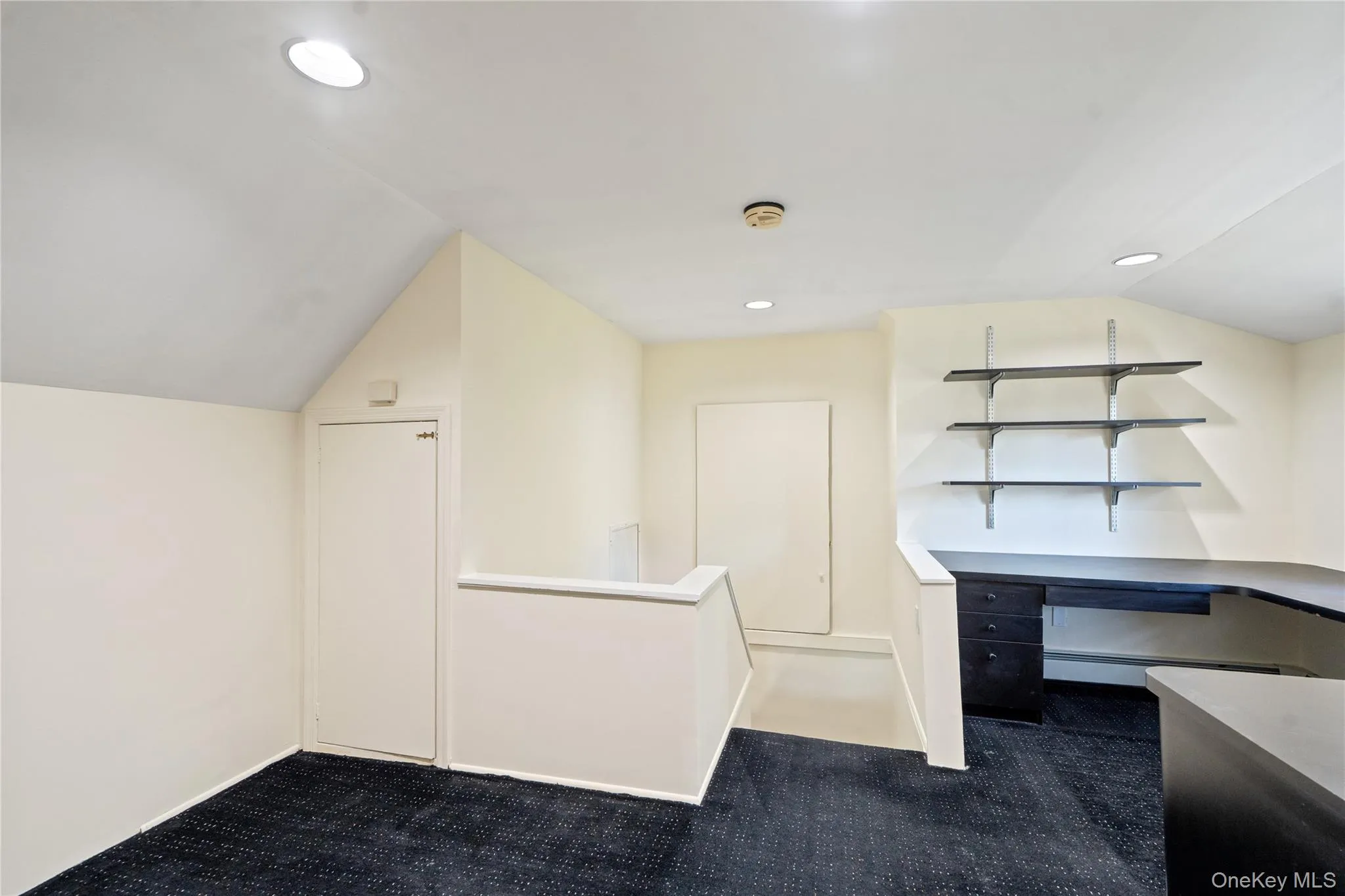 Unfurnished office featuring dark colored carpet, lofted ceiling, and recessed lighting Unfurnished office featuring dark colored carpet, lofted ceiling, and recessed lighting