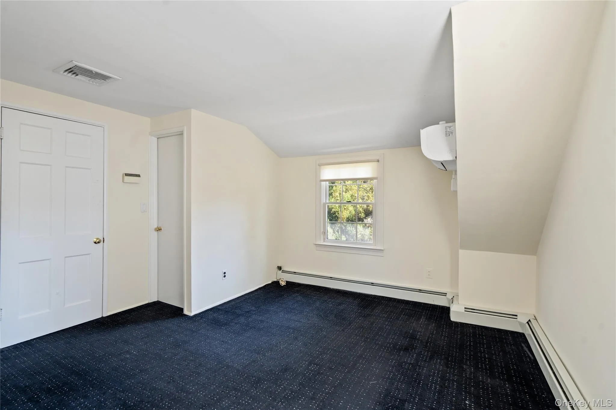 Bonus room with vaulted ceiling, baseboard heating, dark carpet, and an AC wall unit Bonus room with vaulted ceiling, baseboard heating, dark carpet, and an AC wall unit