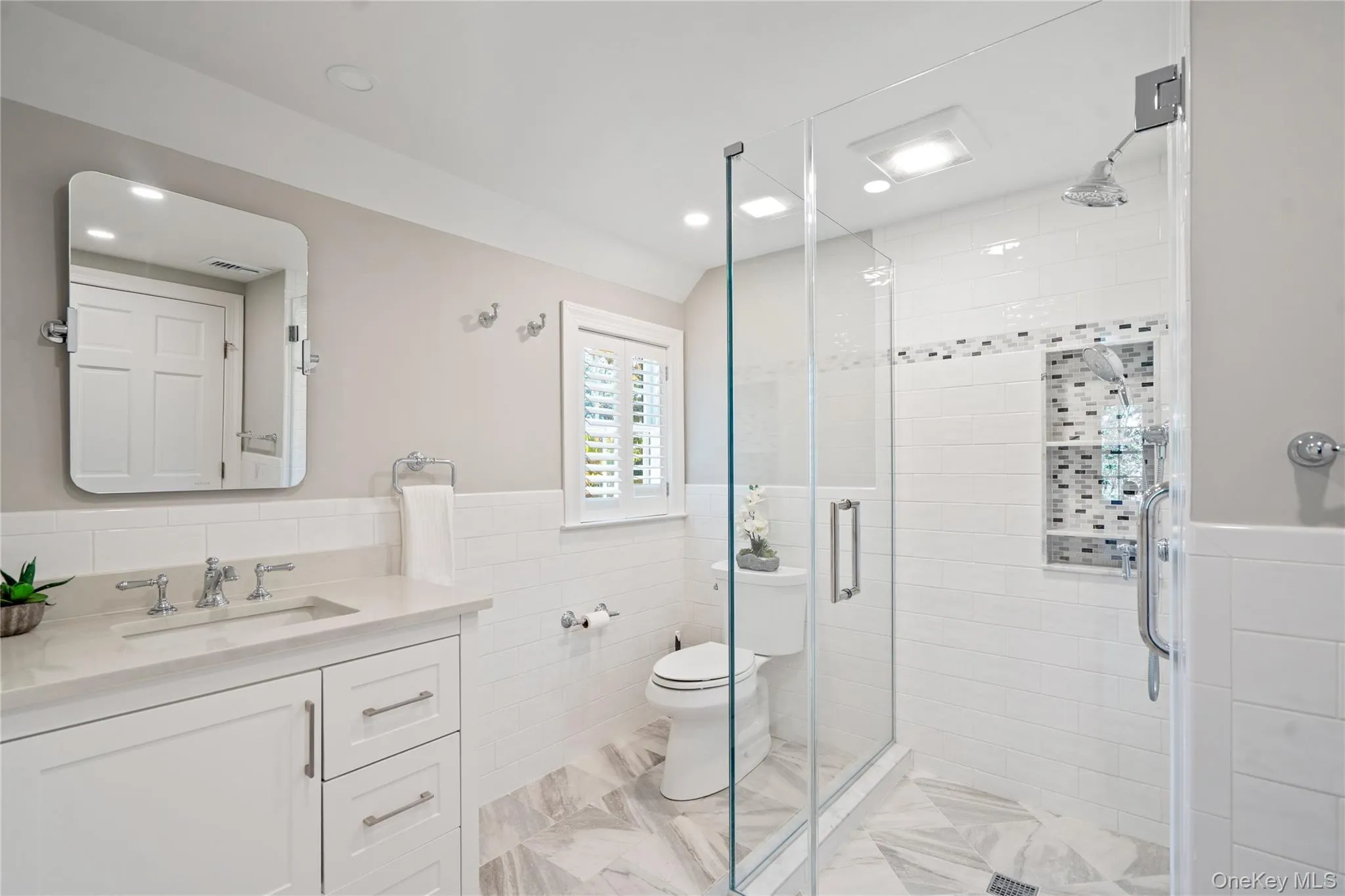 Bathroom with vanity, a wainscoted wall, tile walls, and a shower stall Bathroom with vanity, a wainscoted wall, tile walls, and a shower stall