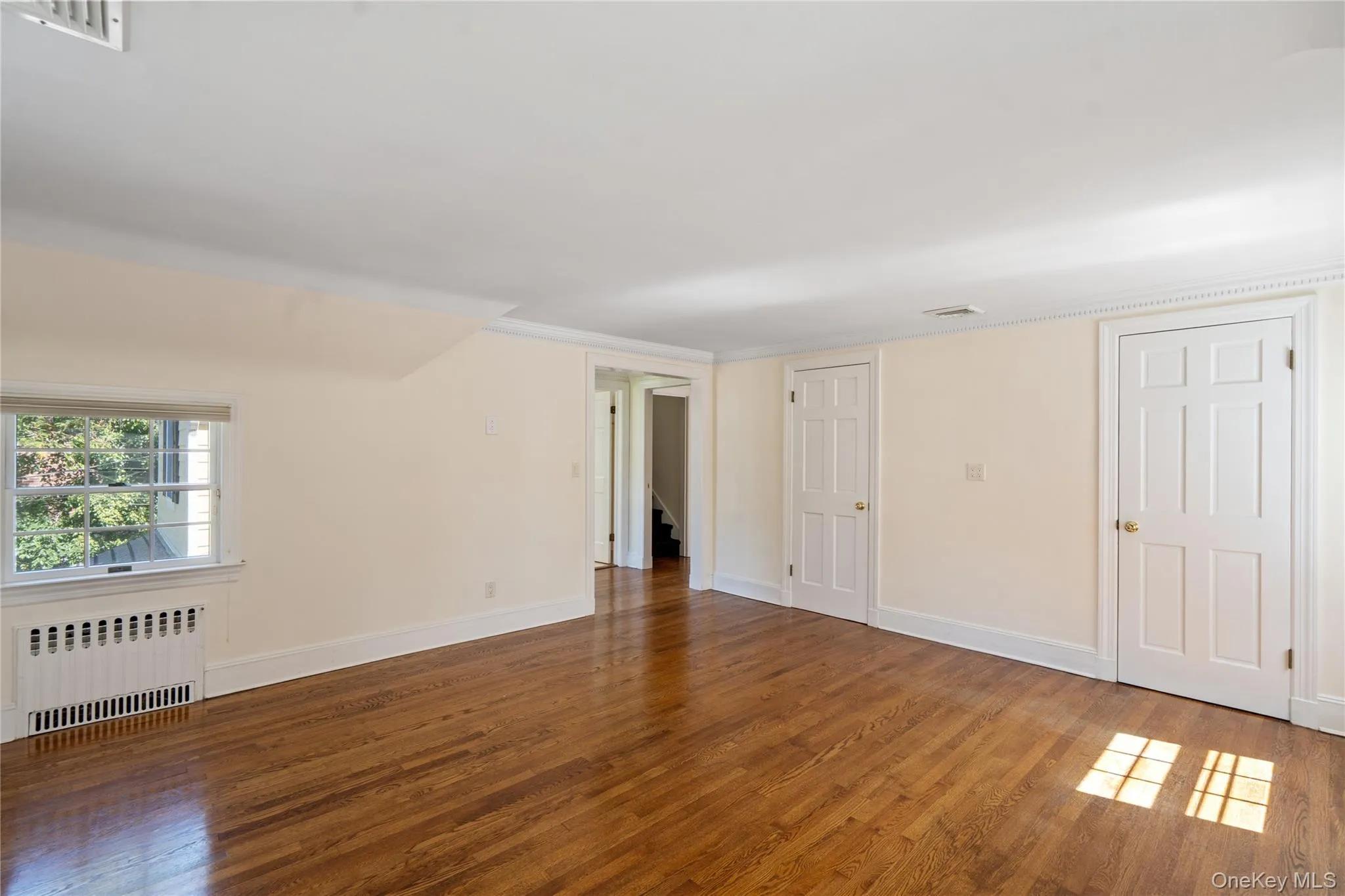 Unfurnished room with radiator heating unit and wood finished floors Unfurnished room with radiator heating unit and wood finished floors