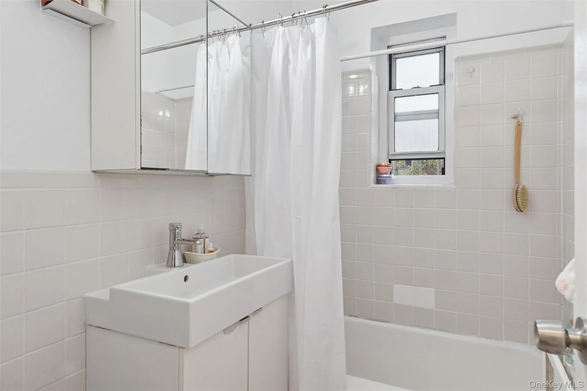 Full bath with vanity, shower / bath combo with shower curtain, and tile walls Full bath with vanity, shower / bath combo with shower curtain, and tile walls